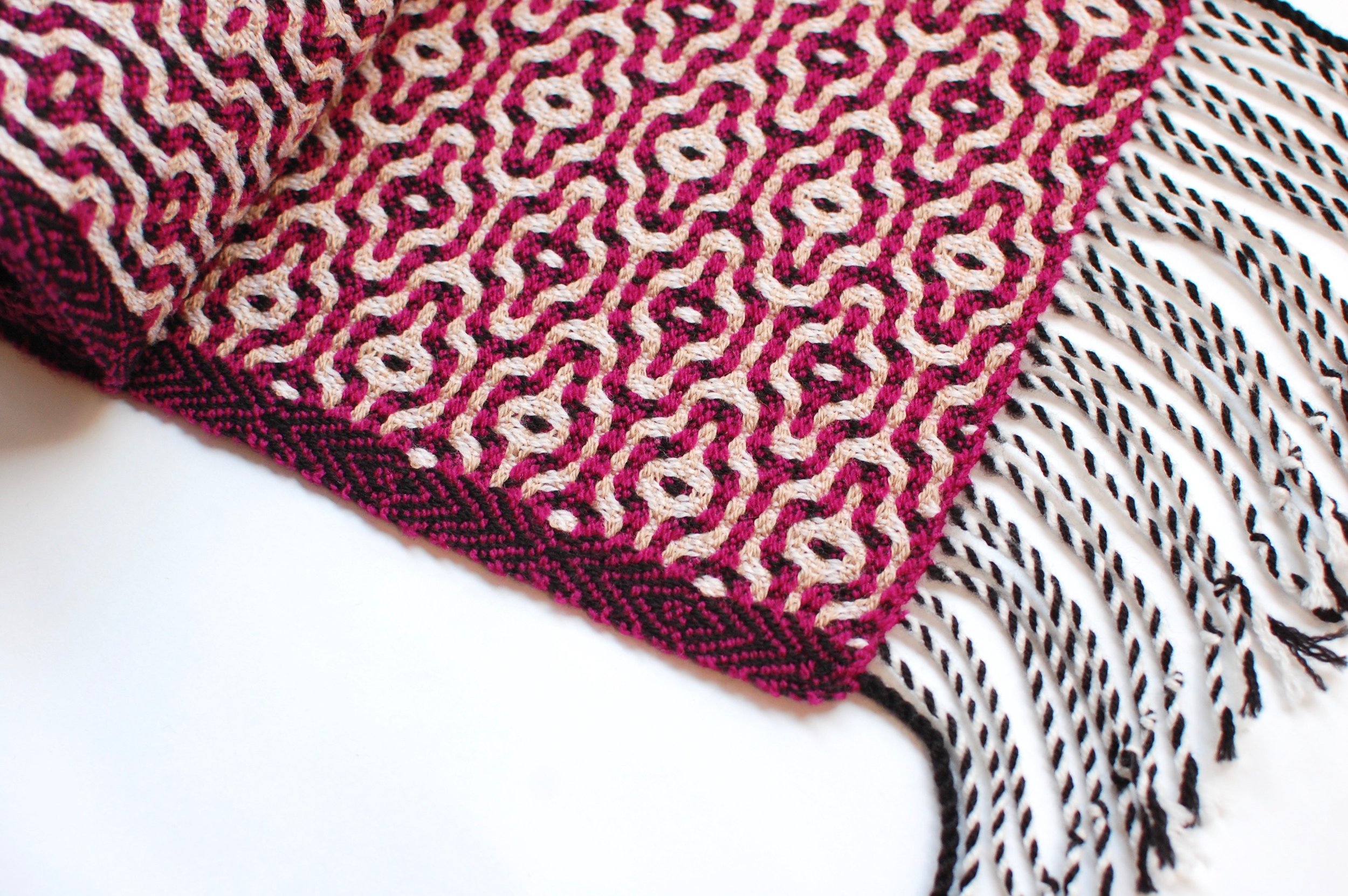 detail of a handwoven scarf with twisted fringe.