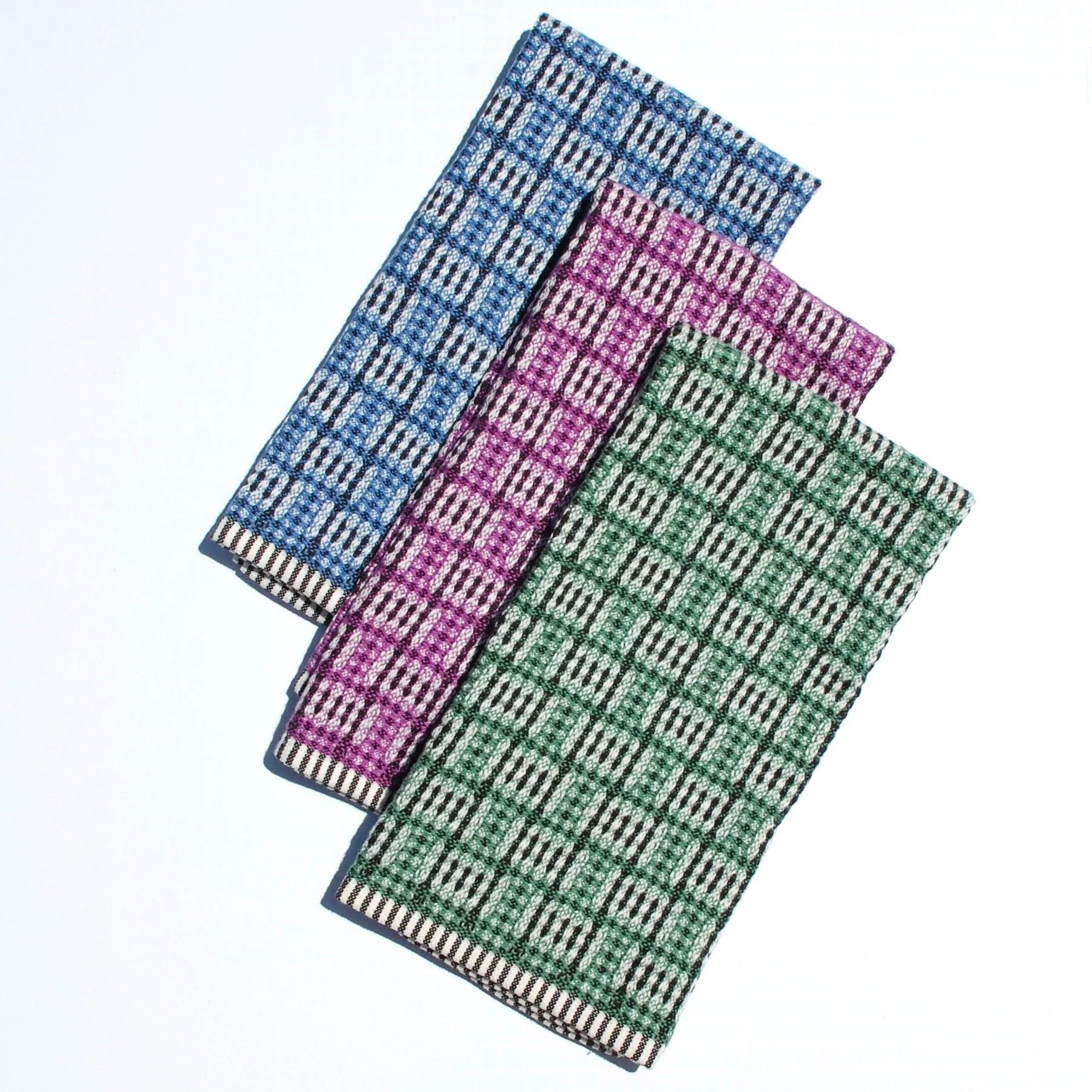 A trio of cheerful handwoven towels in blue, pink/purple and green