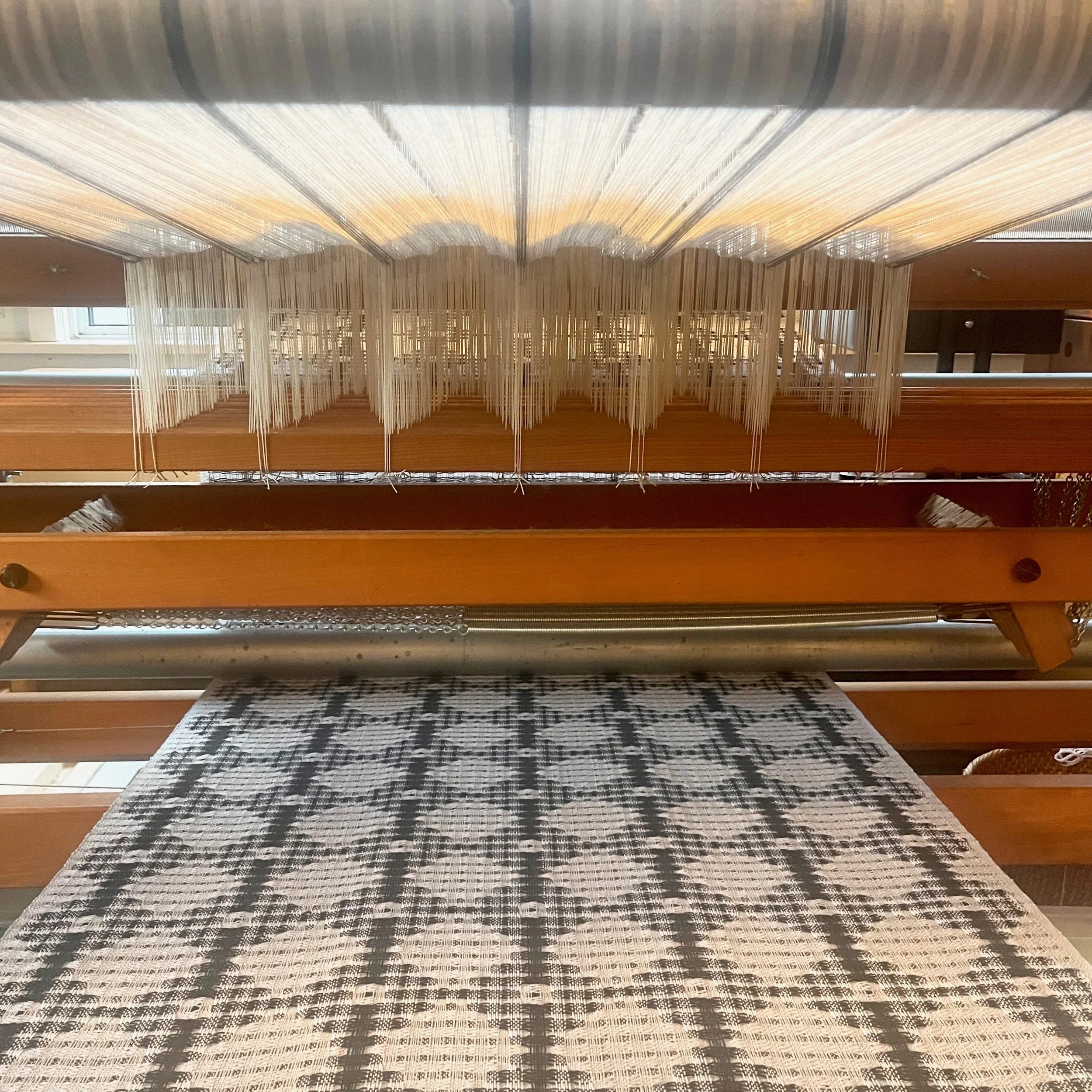 Merino wool being woven on an AVL loom. The cloth is traveling under the loom to the cloth storage take up beam.