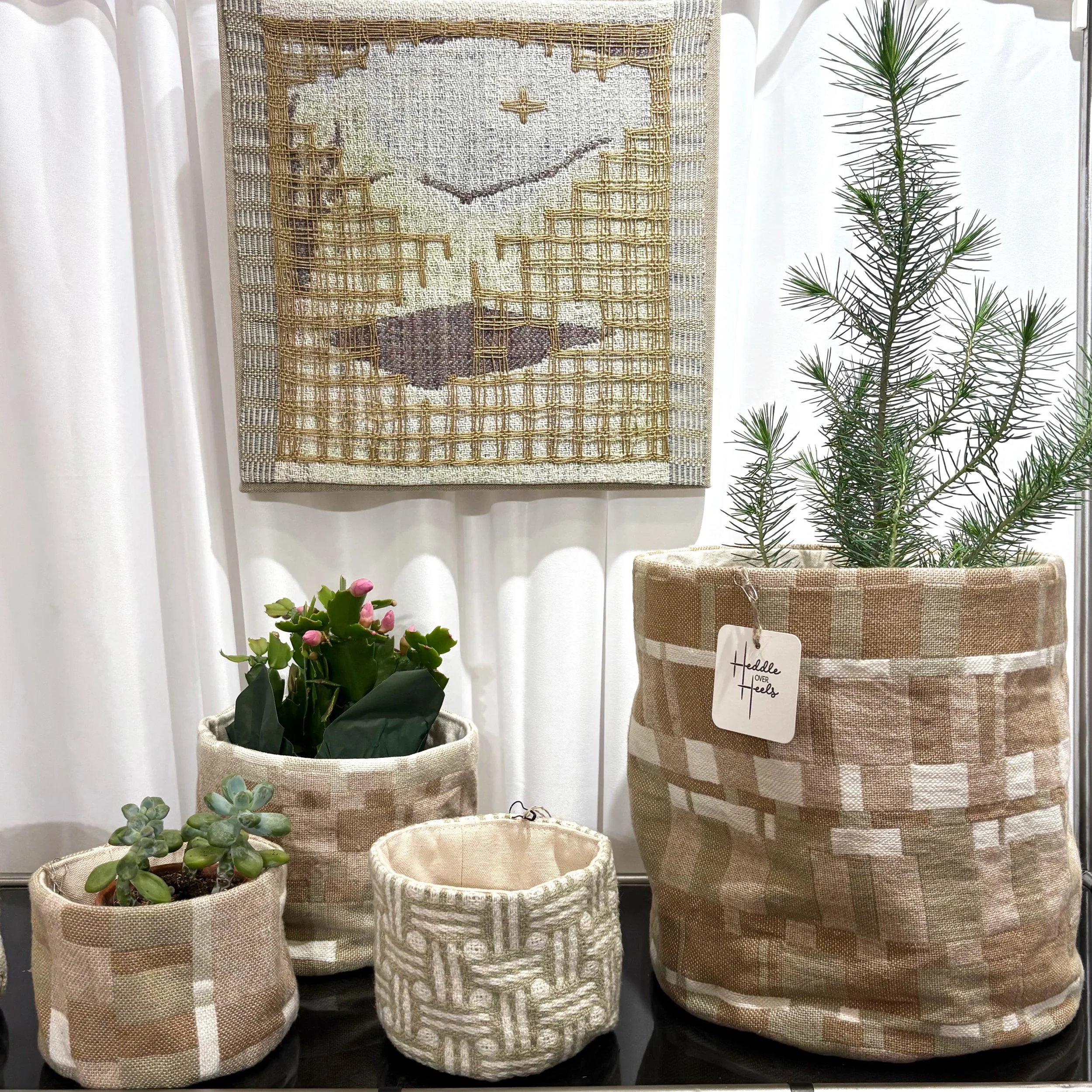 A collection of plant pots made from handwoven fabric on display at a fine art and craft show.