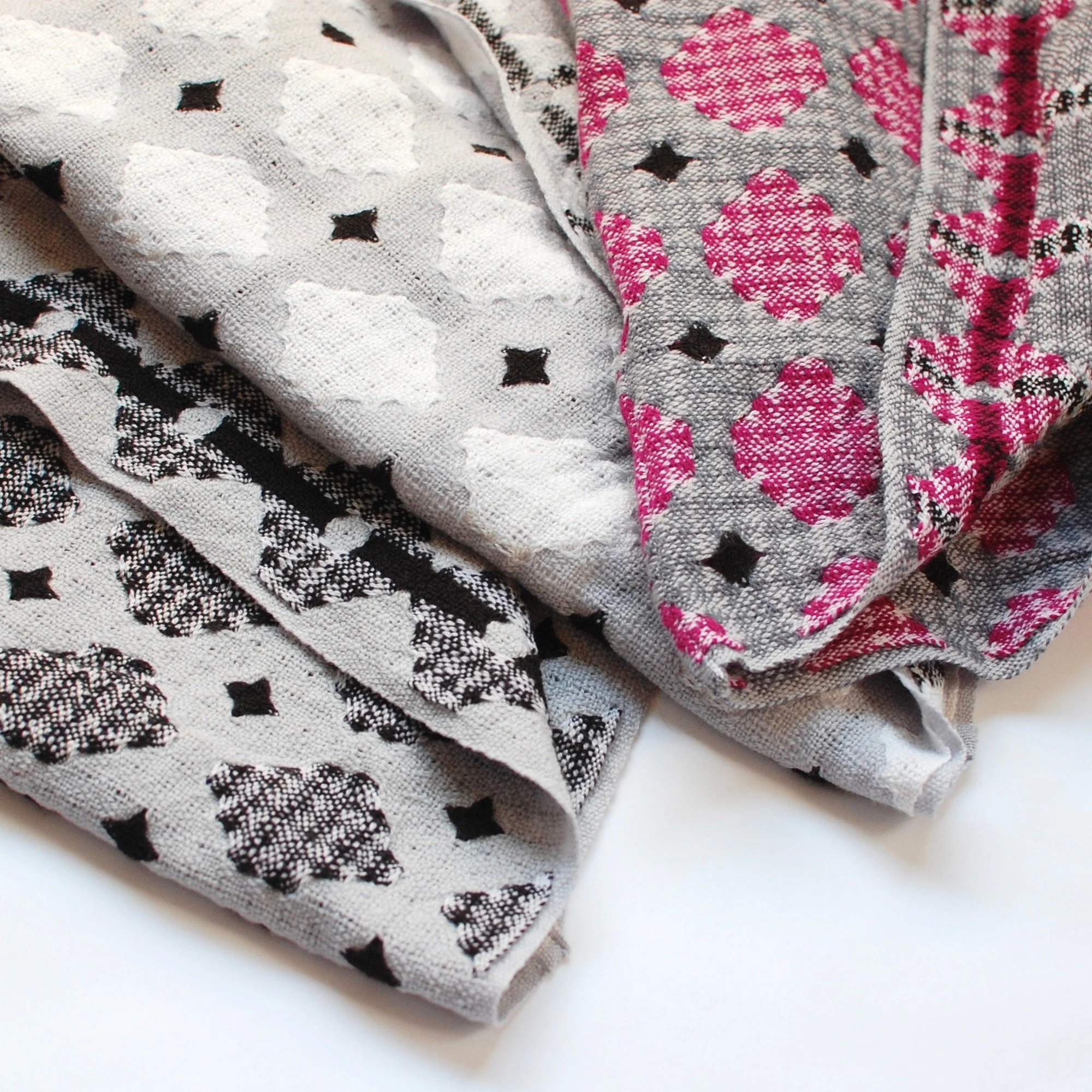 Merino handwoven scarves shown in three different colors. Pink, black, grey, and white.