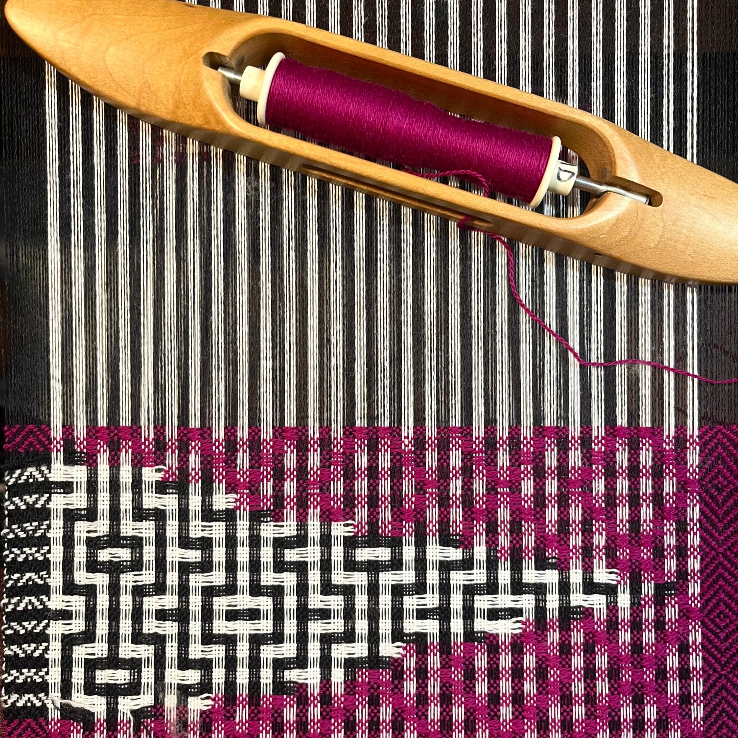 A handwoven scarf being woven on a loom with a boat shuttle. Modern handwoven textile