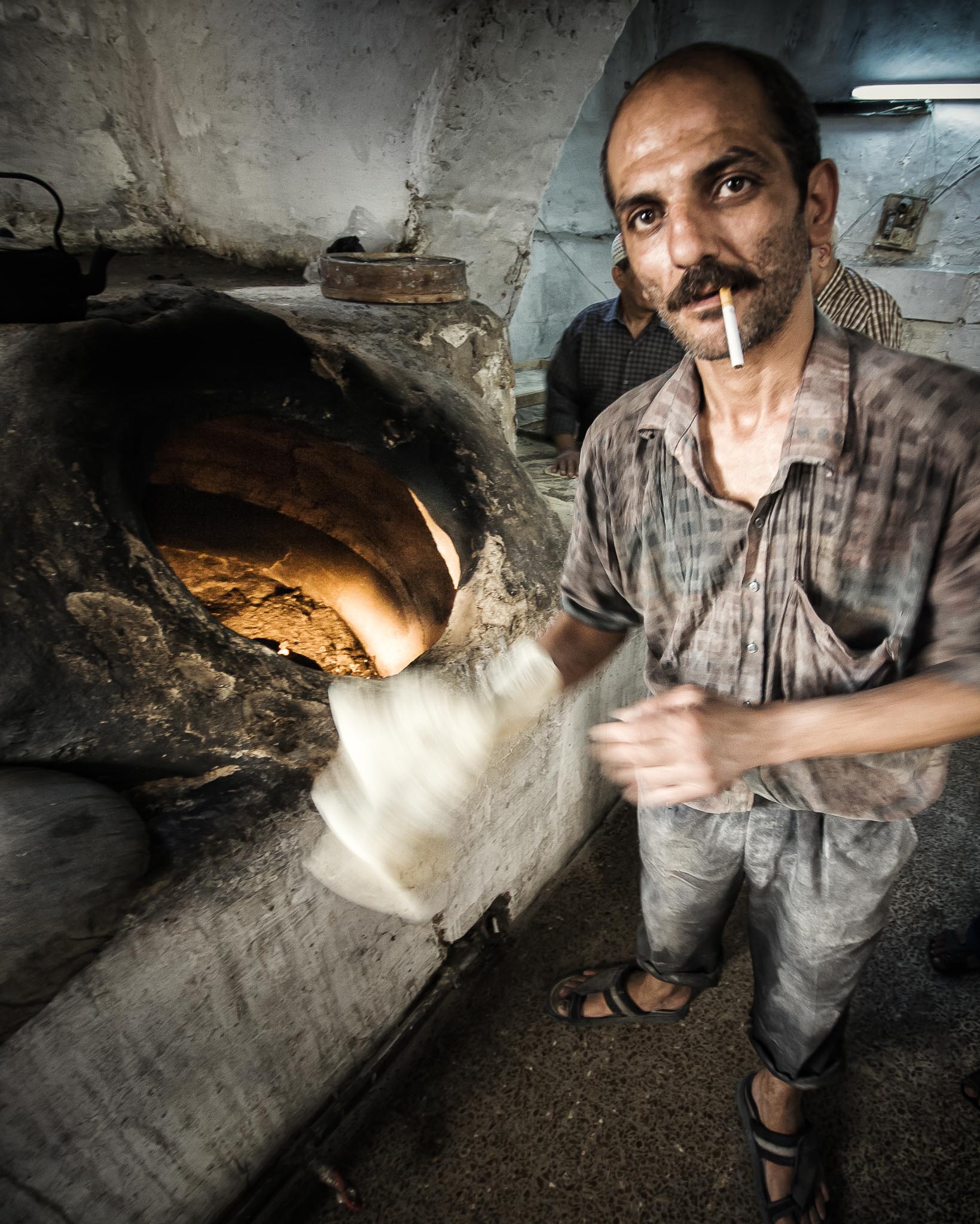 The Baker: Flat slabs of dough is slapped to the inside wall of these kilns to become flat breads (Damascus).