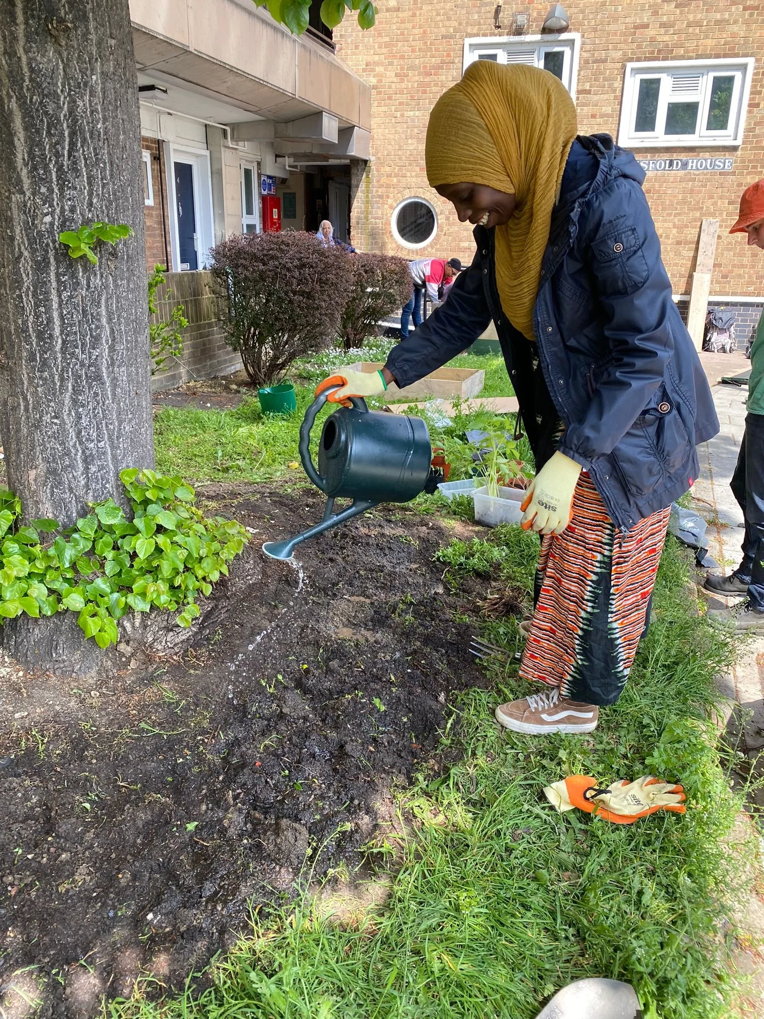 woman watering seedlings in new flowerbed