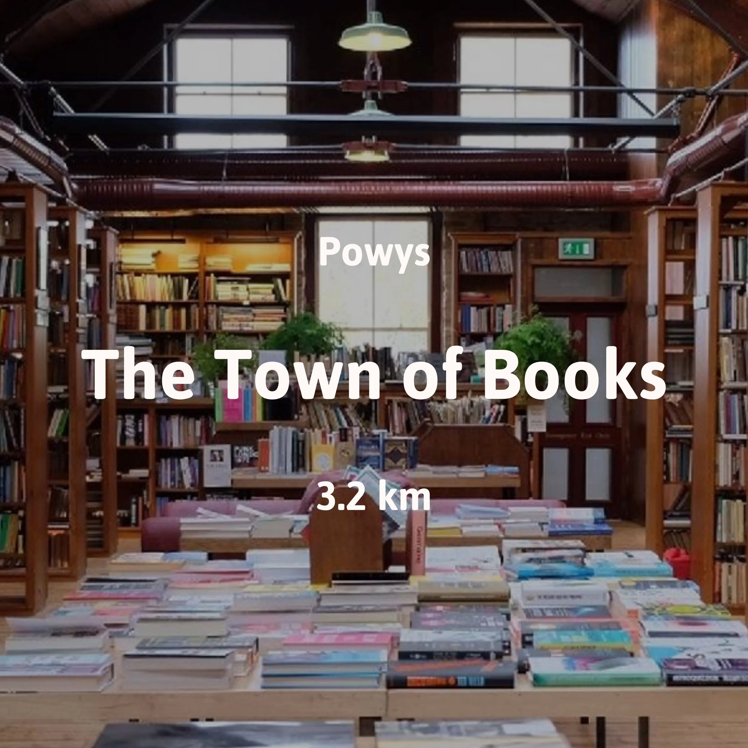 Inside a book shop in Hay-on-Wye. A central table with piles of colourful books and a vaulted ceiling with bookshelves around the walls.