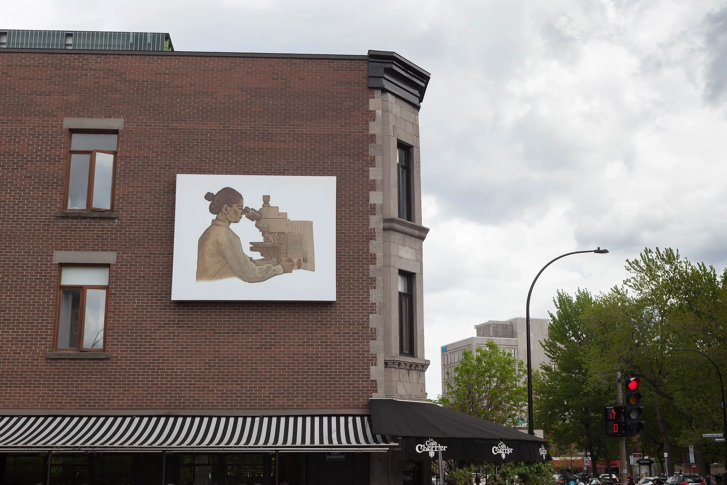  © Life of a Craphead,  $100 Bill With South Asian Scientist Added Back In  (2019). Vue d’installation, Dazibao, 2019. Façade du Café Cherrier. Photo : Marilou Crispin. 