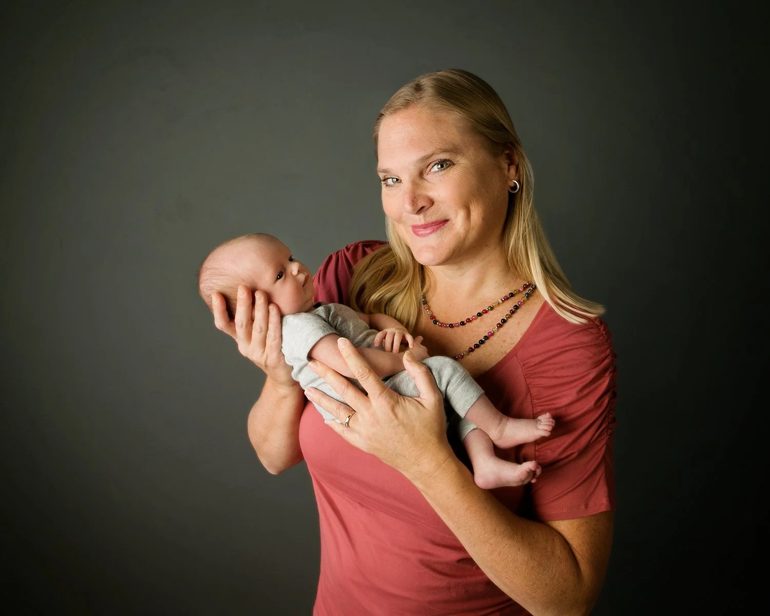 owner of of ABC Doulas smiling for photo in Portland Oregon with a newborn client (one of twins).