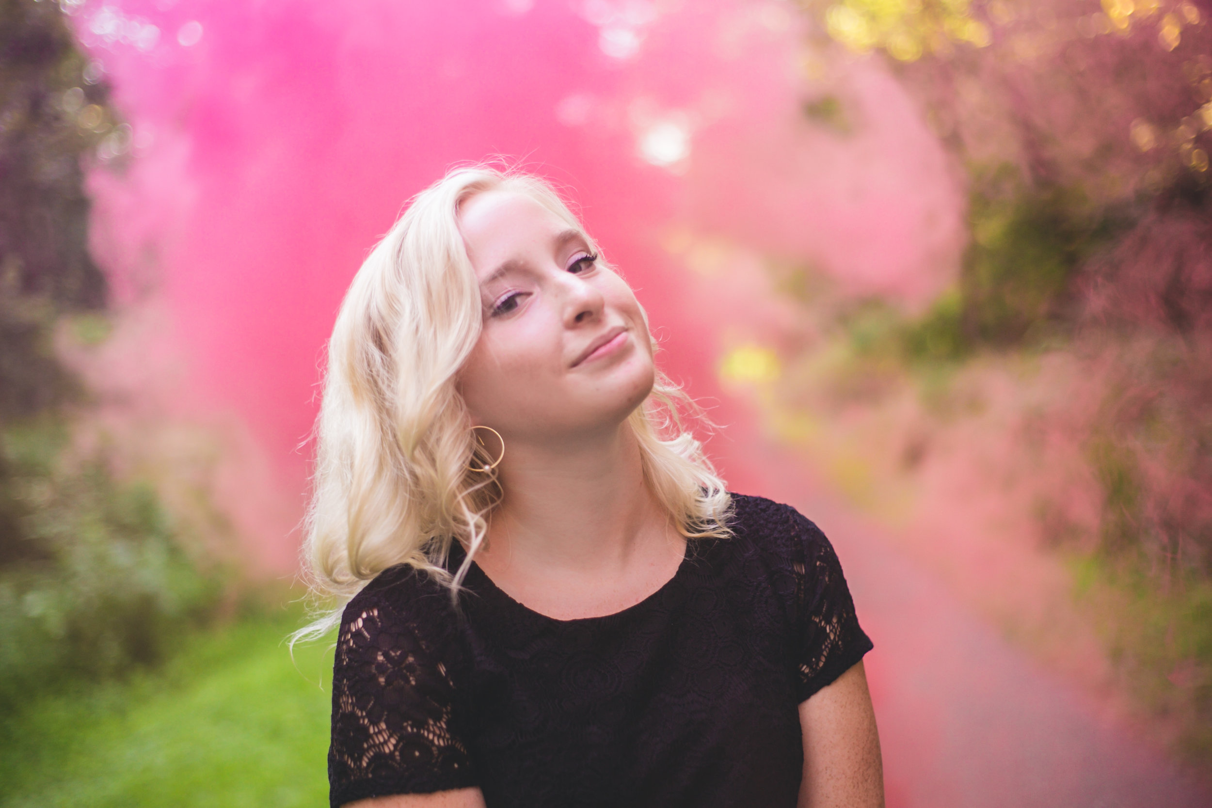 Girl poses in front of pink smoke bombs in Stillwater MN