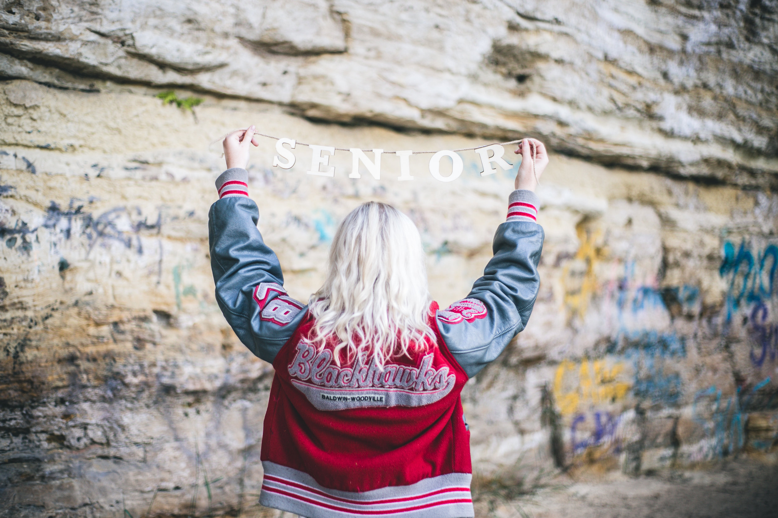 Baldwin WI high school senior holds sign at caves at boom site in Stillwater MN