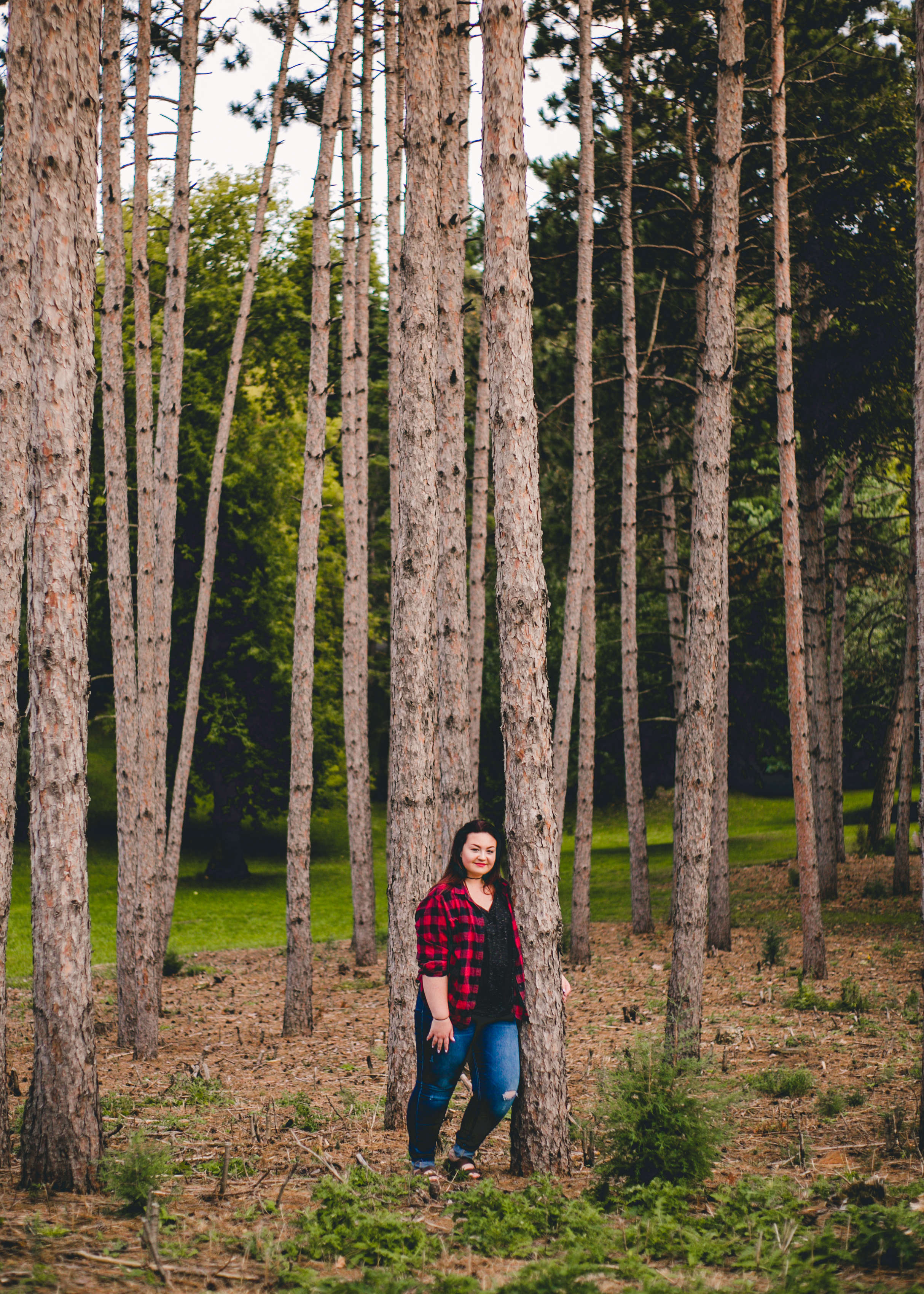 Senior in flannel posing against trees