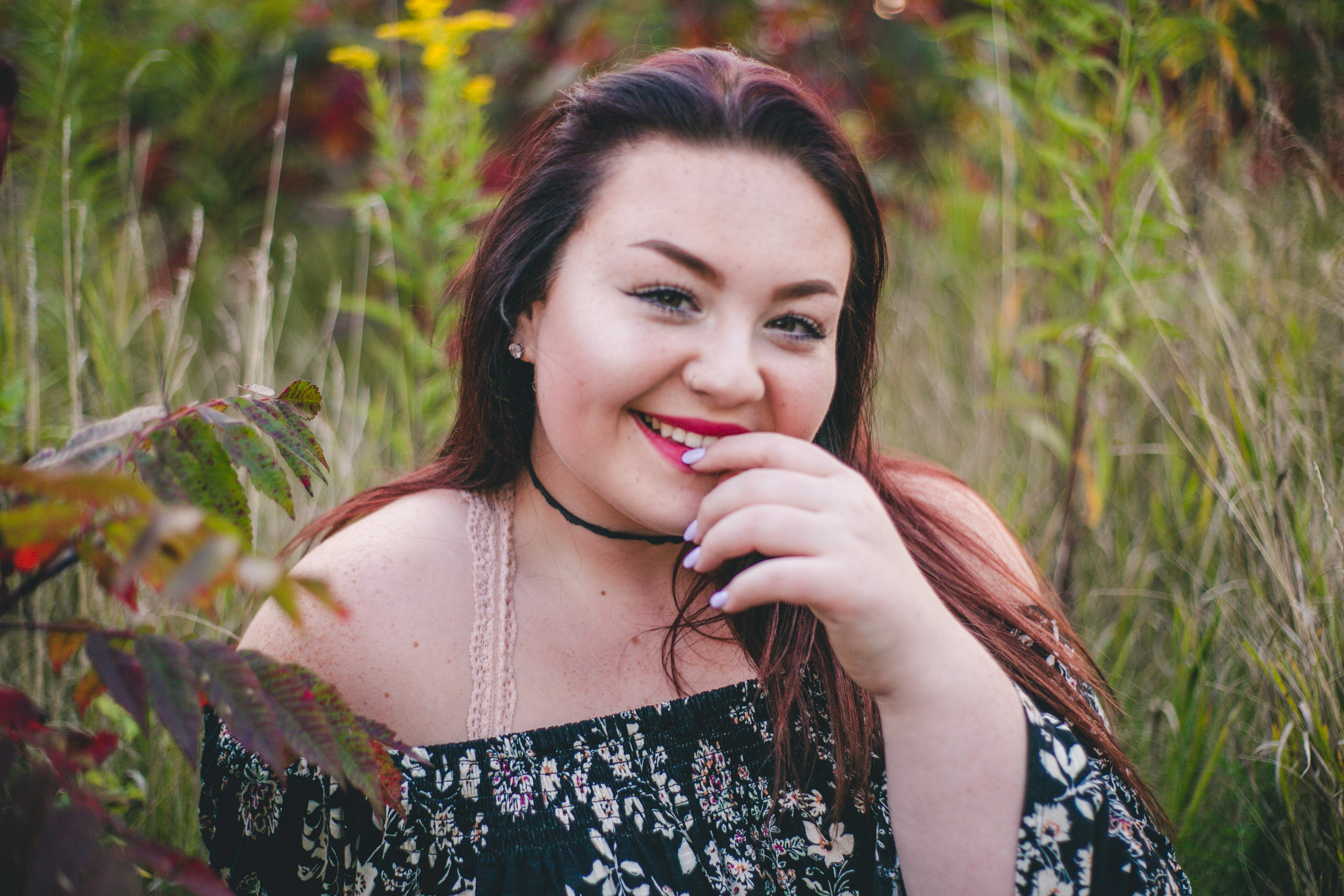 Smiling high school senior with long nails in meadow in Hudson WI
