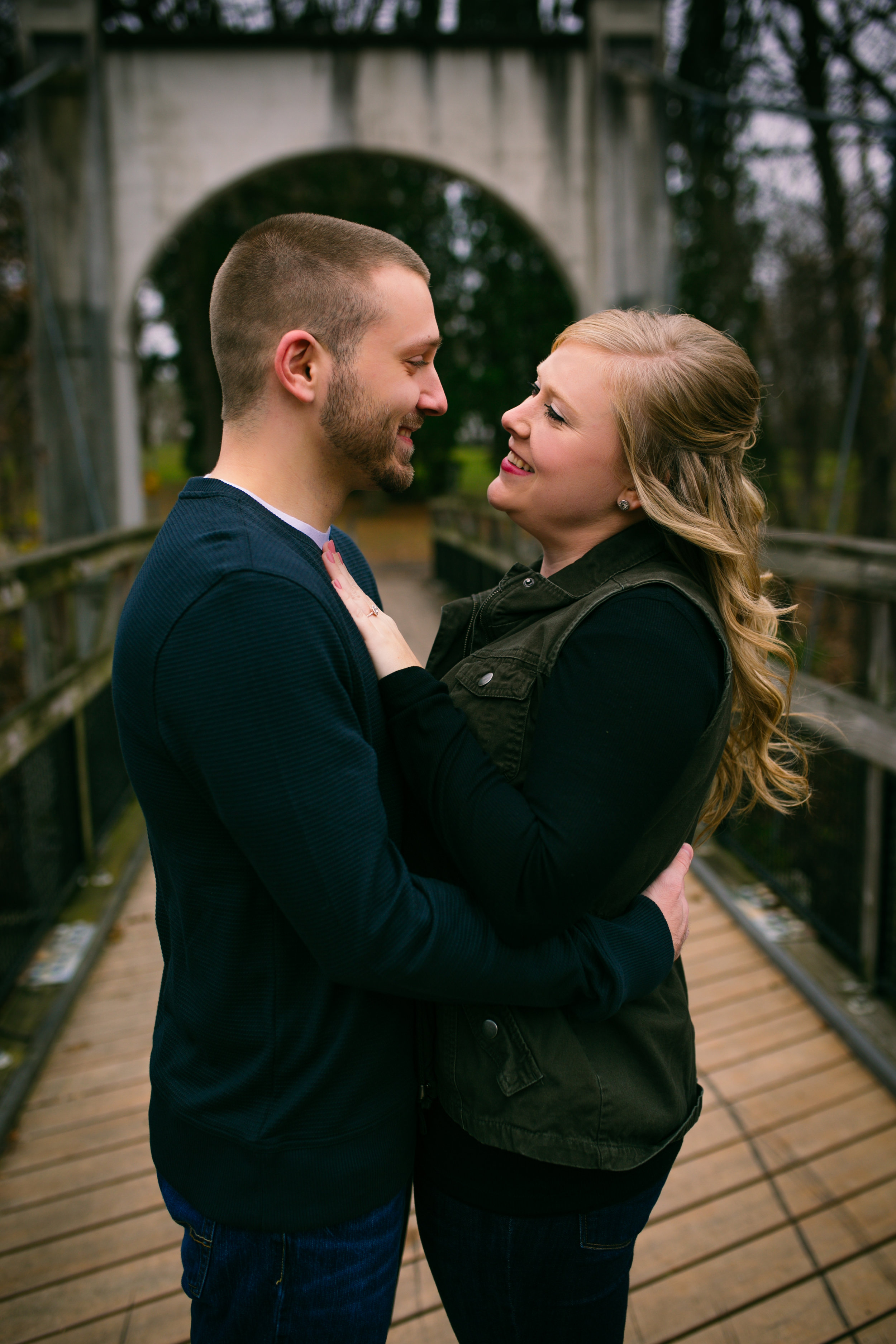 couple smiling and cuddling on Glen Park bridge in River Falls