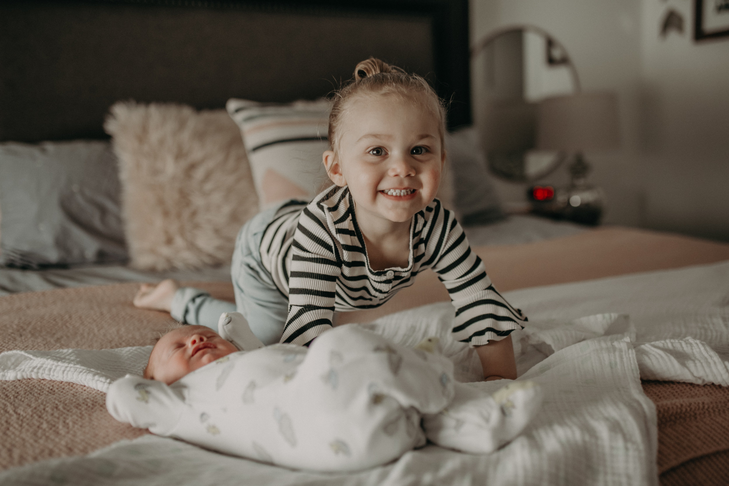 big sister smiling at little brother on bed