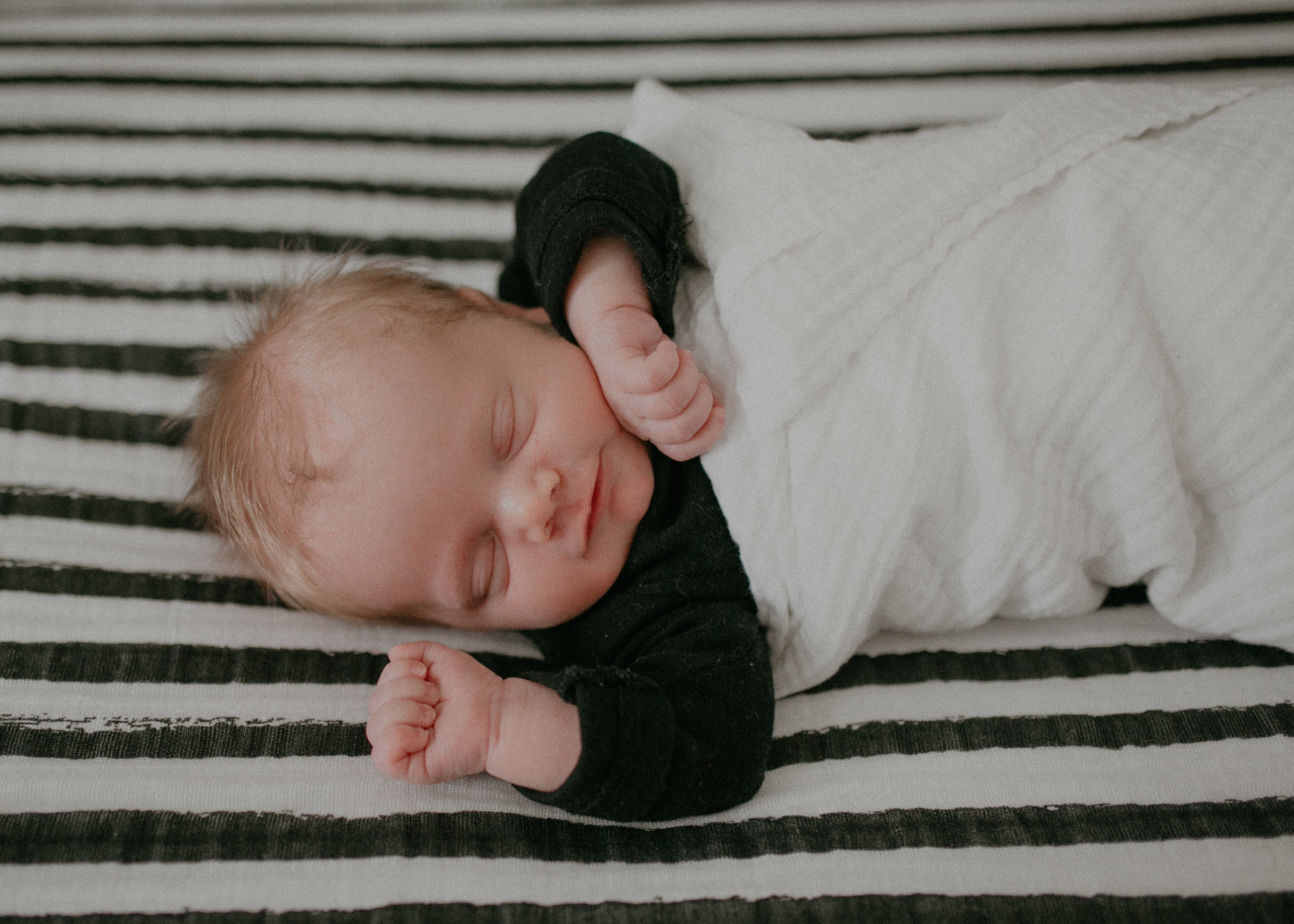 smiling newborn baby boy on black and white striped sheet