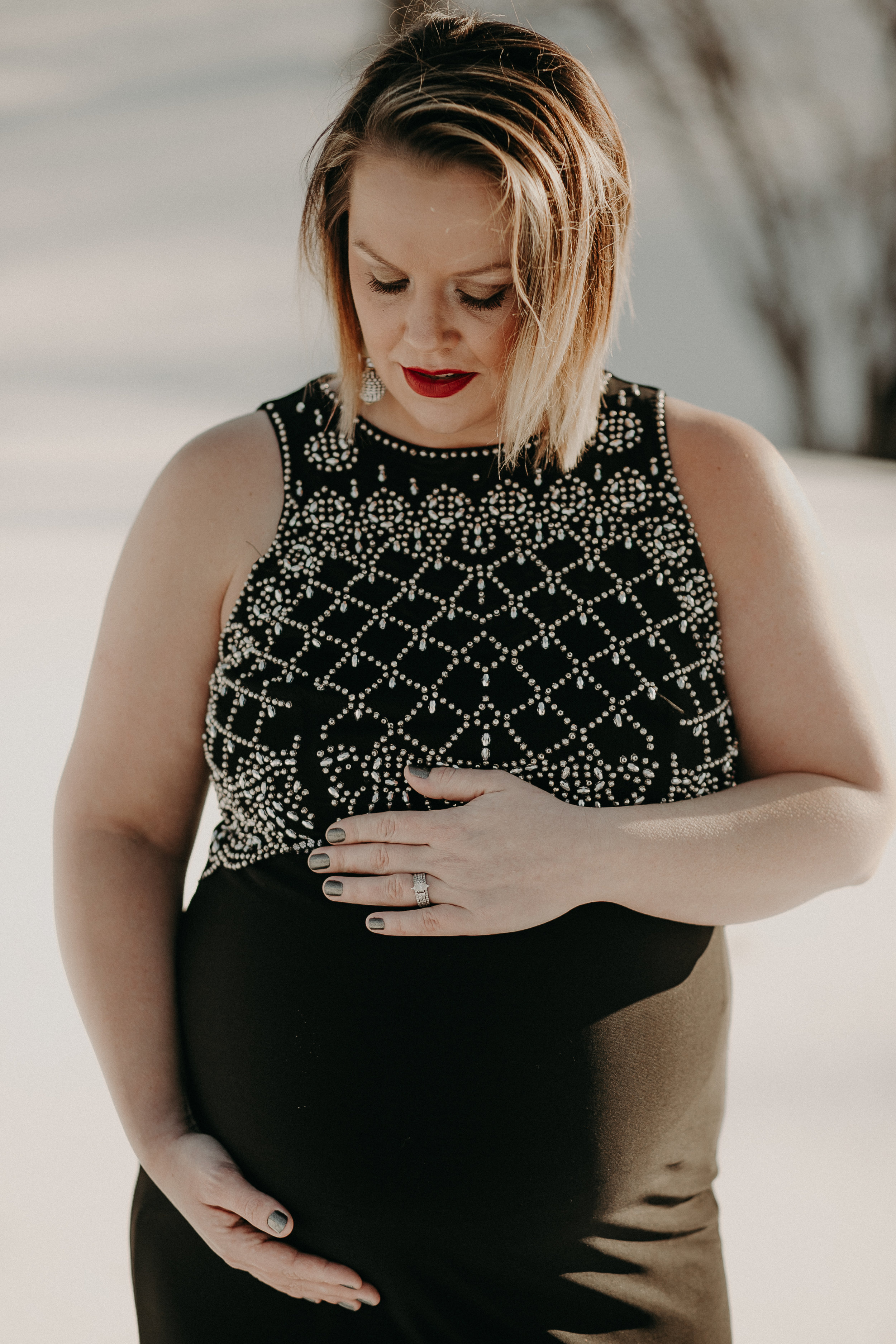 pregnant mom holding belly in black dress in river falls wi