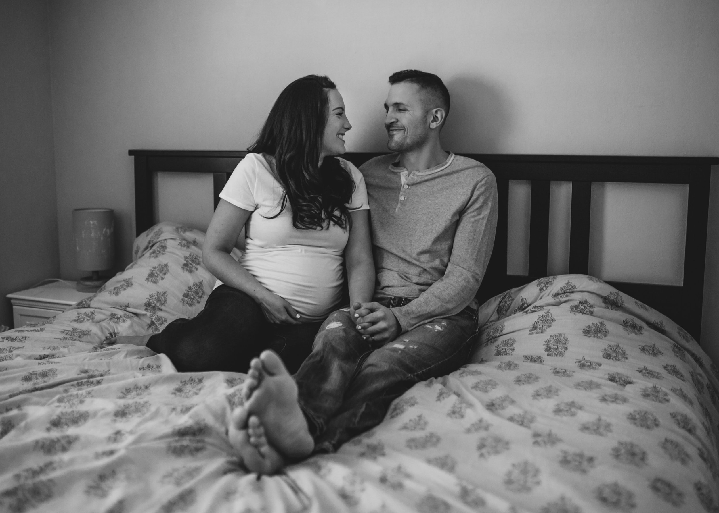 couple_expecting_baby_on_bed_laughing.jpg