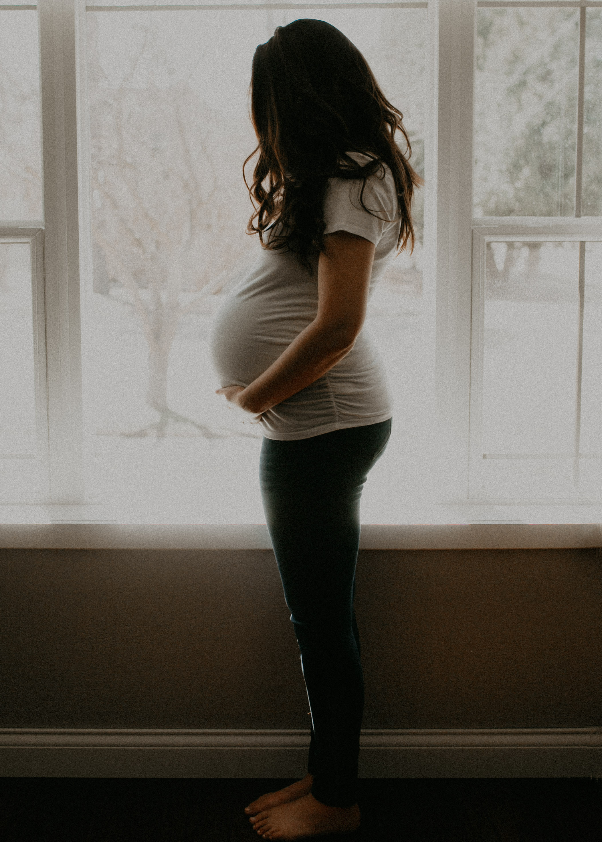 pregnant_woman_holding_belly_natural_light_window.jpg
