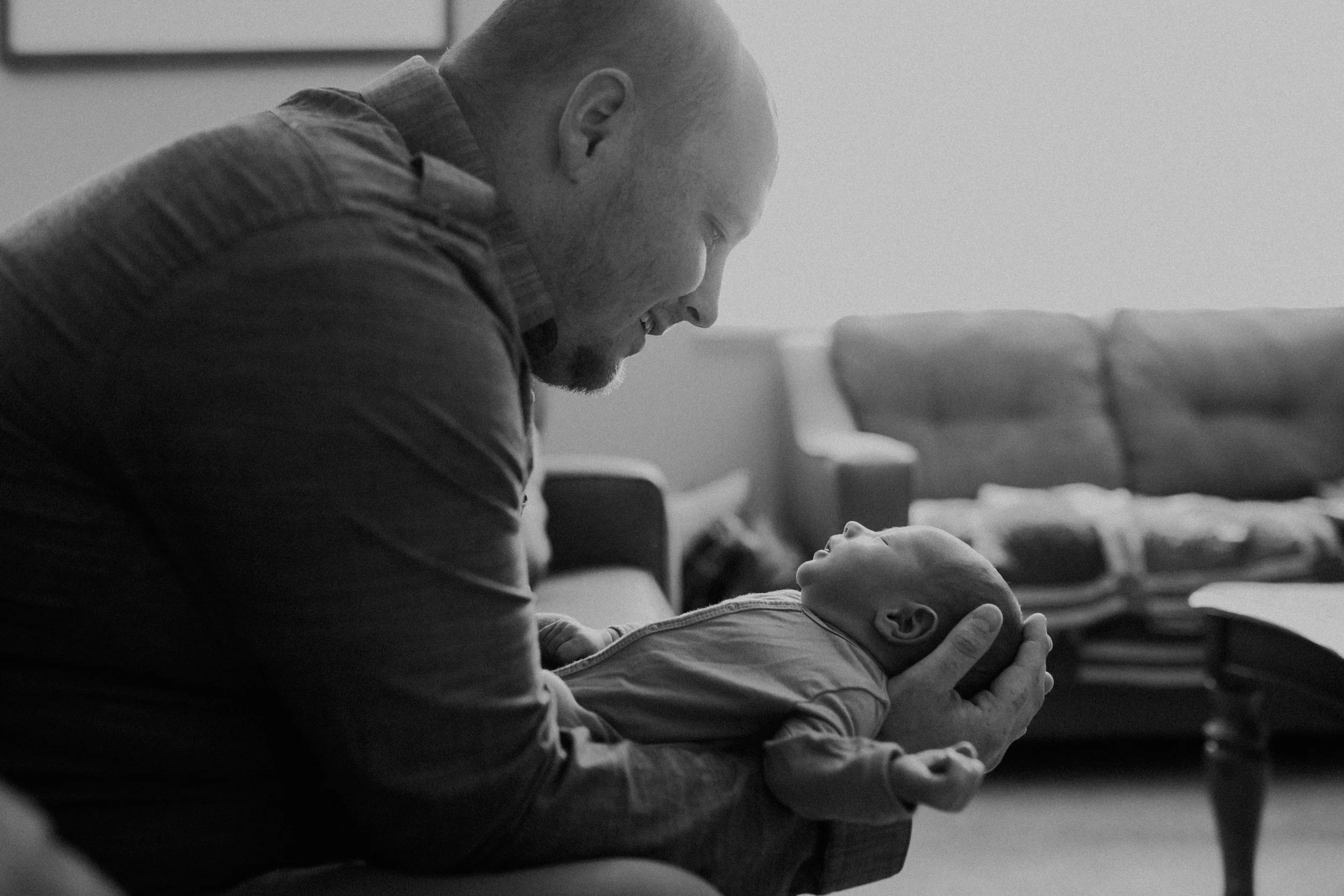 black and white photo of Chaska MN dad holding newborn baby boy in his home