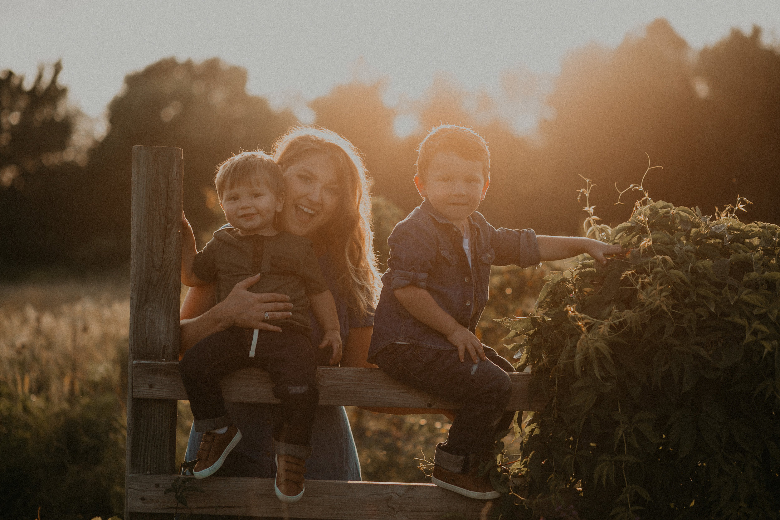  smiling mommy in River Falls Wisconsin during golden hour sunset holding sons 