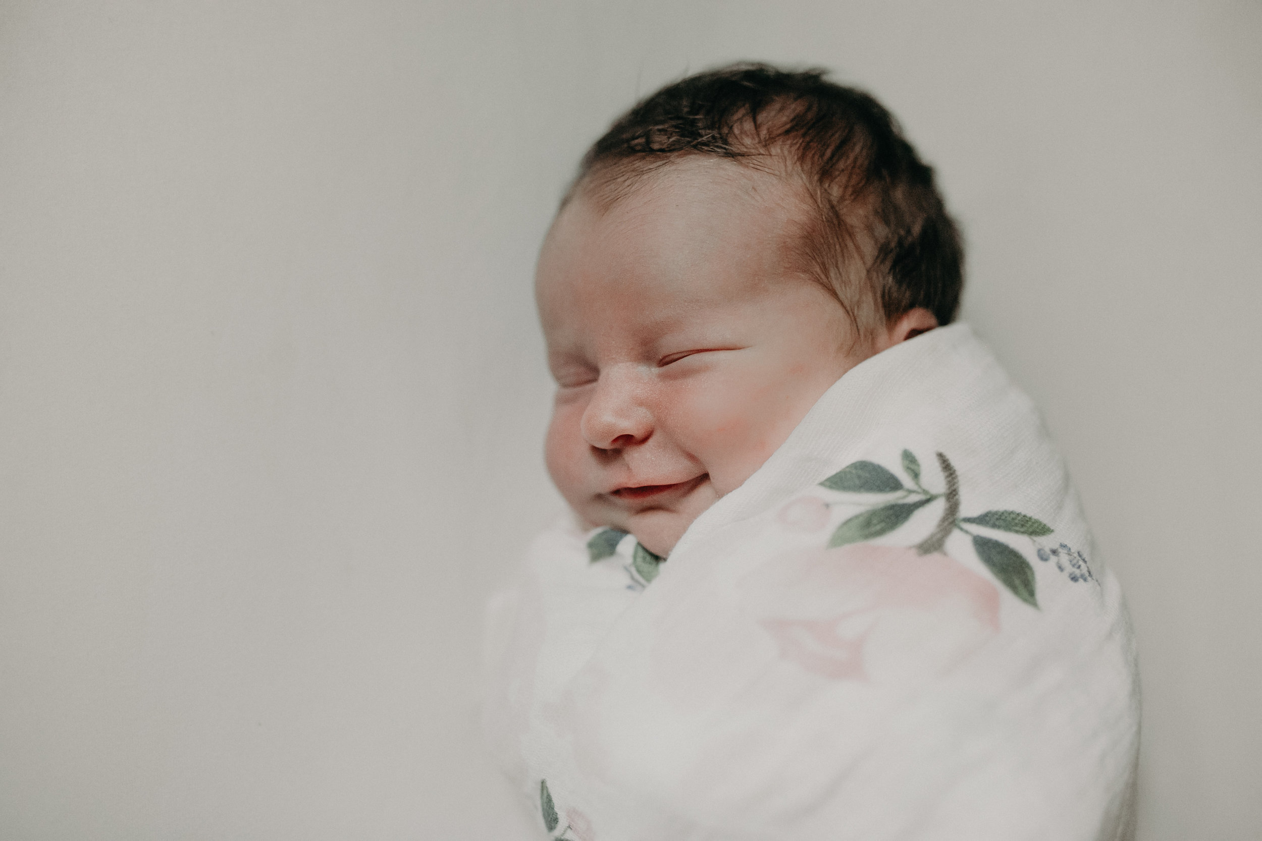smiling newborn abby girl in flower wrap