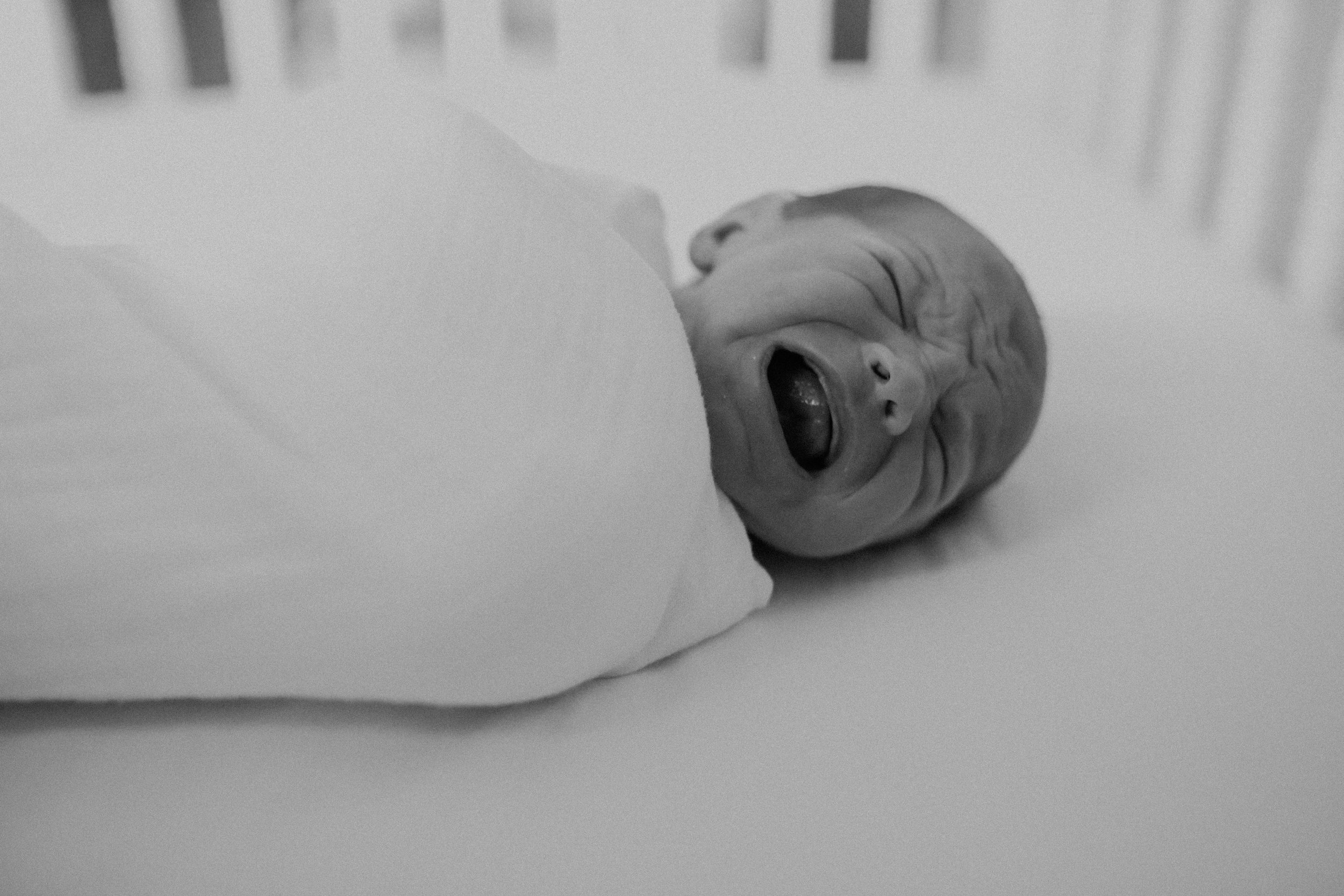  black and white photo of baby crying in her crib 
