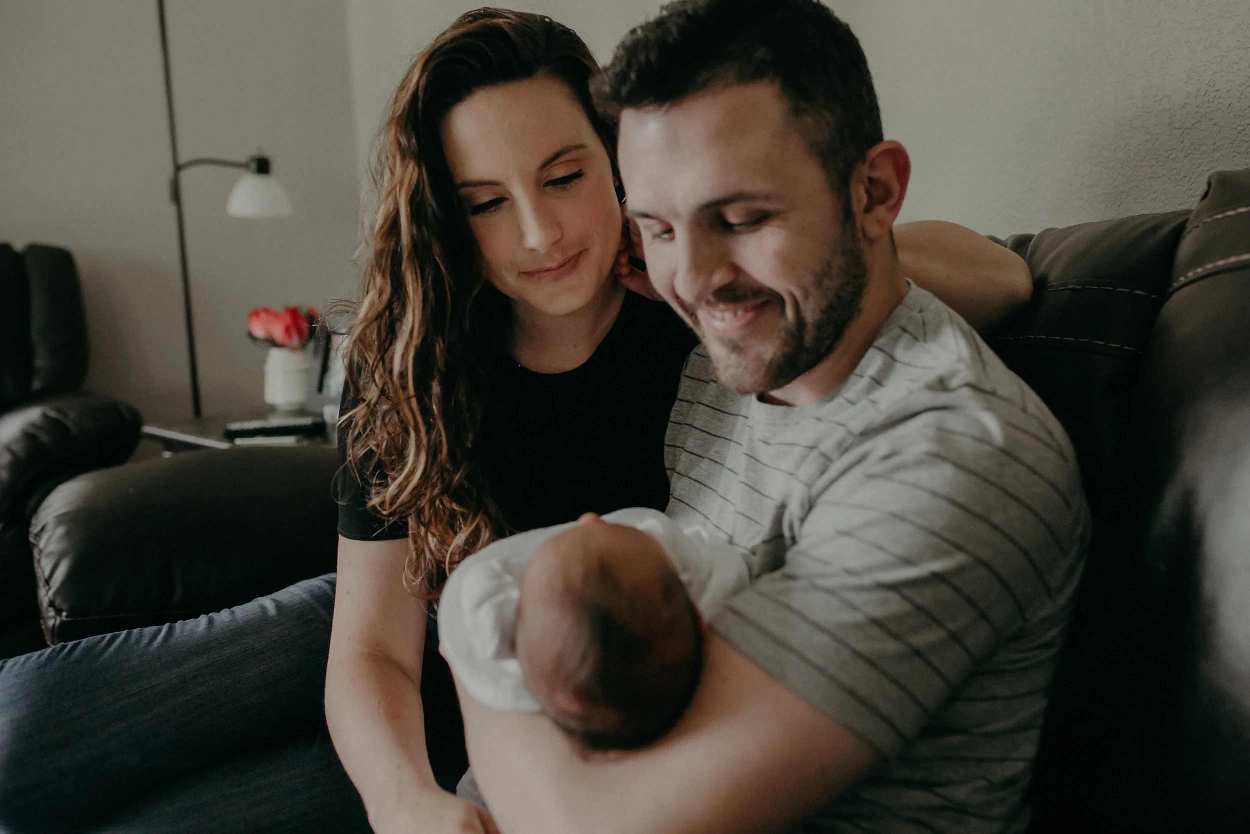 mom and dad smiling at newborn baby during lifestyle in-home session in Marshfield WI