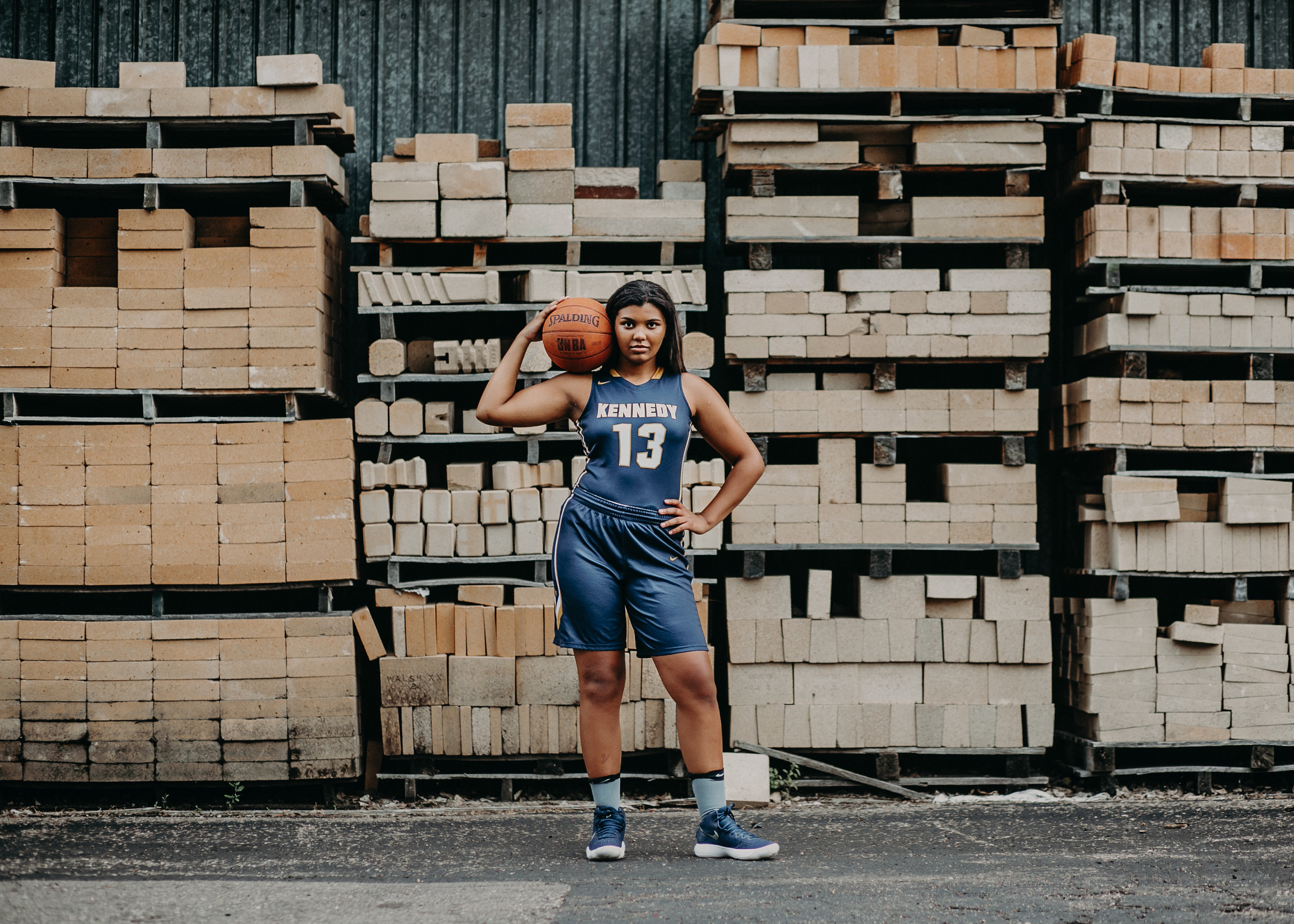 Basketball player in Hudson WI posing by pallets for her senior photo session with Andrea Wagner