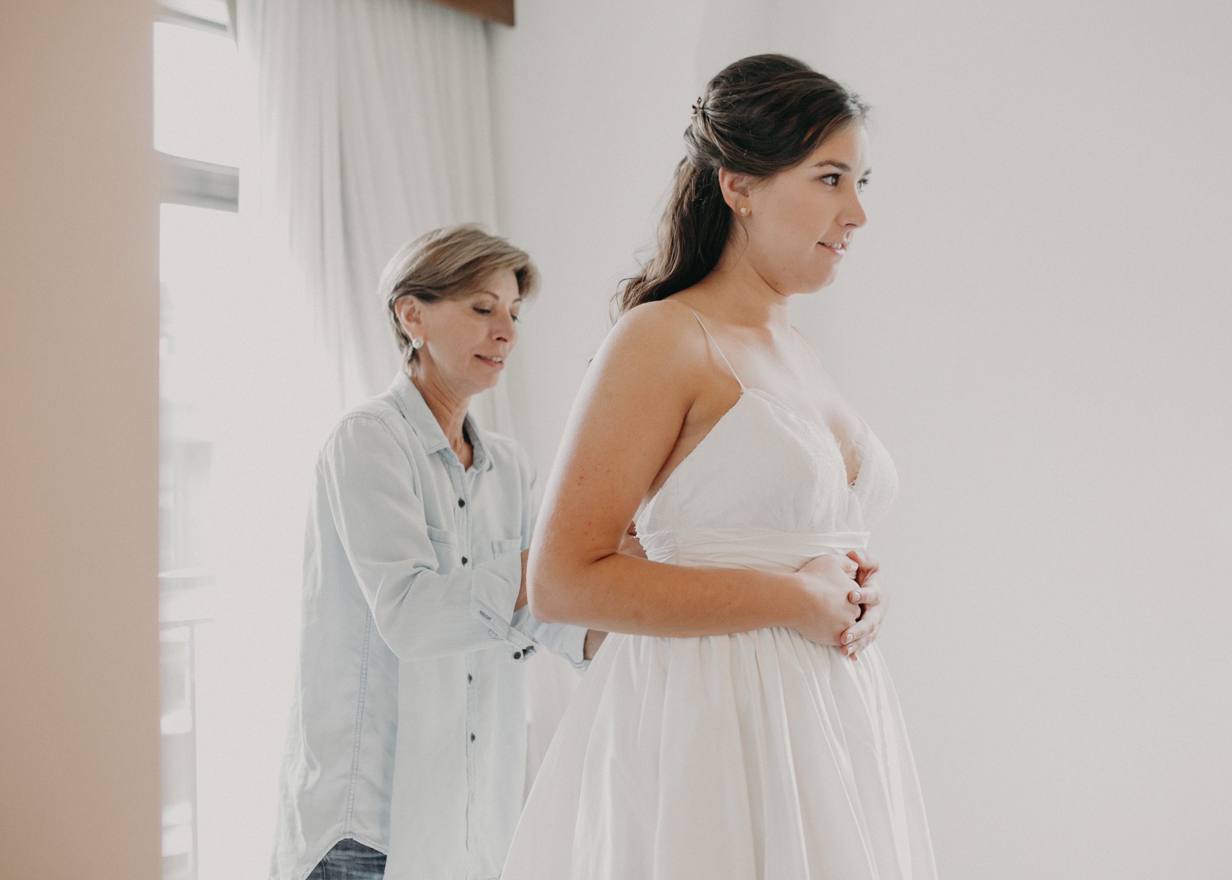 mother of the bride helps bride get into her wedding dress at Hotel Landing in Wayzata MN