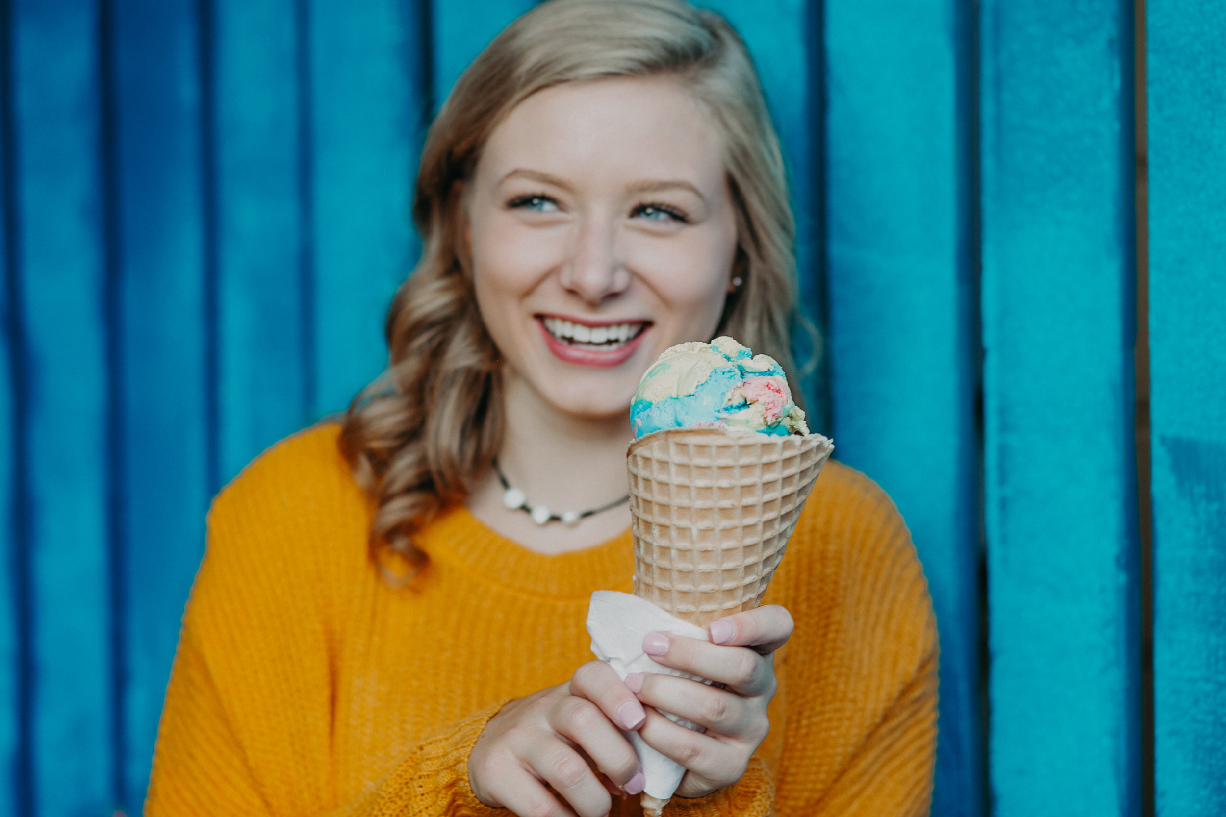 superman ice cream cone held by a smiling senior during her senior photo session in Hudson WI