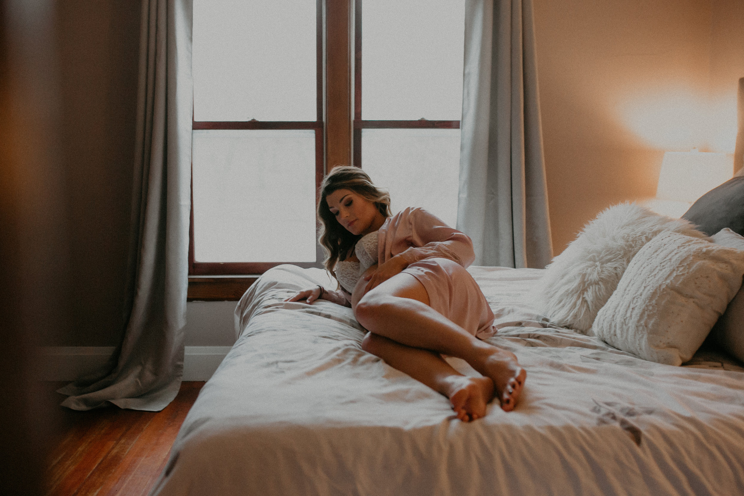 cozy lifestyle maternity session with woman laying on a bed in Osseo WI
