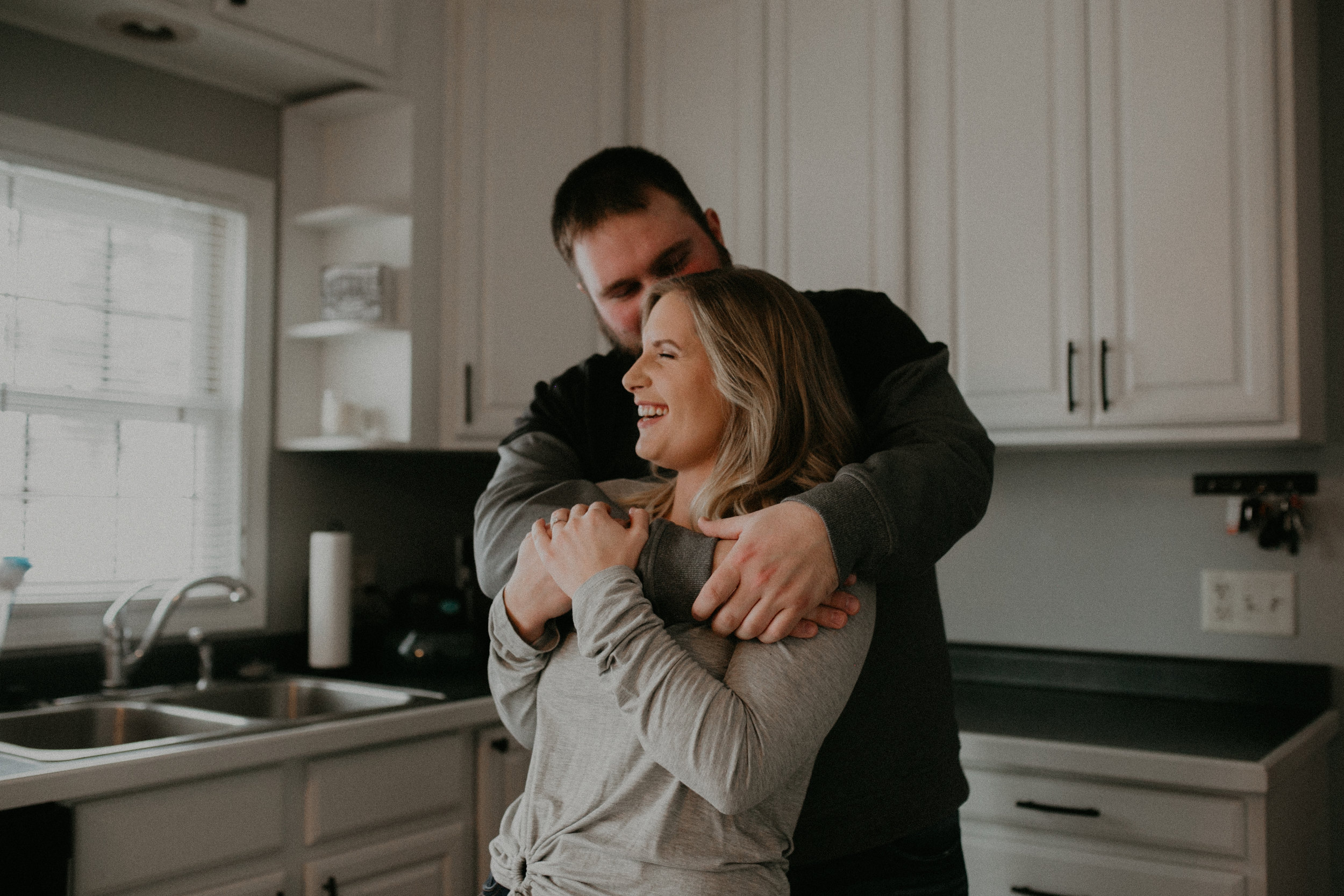  a couple dances and laughs in their kitchen during their engagement session in Athens WI 