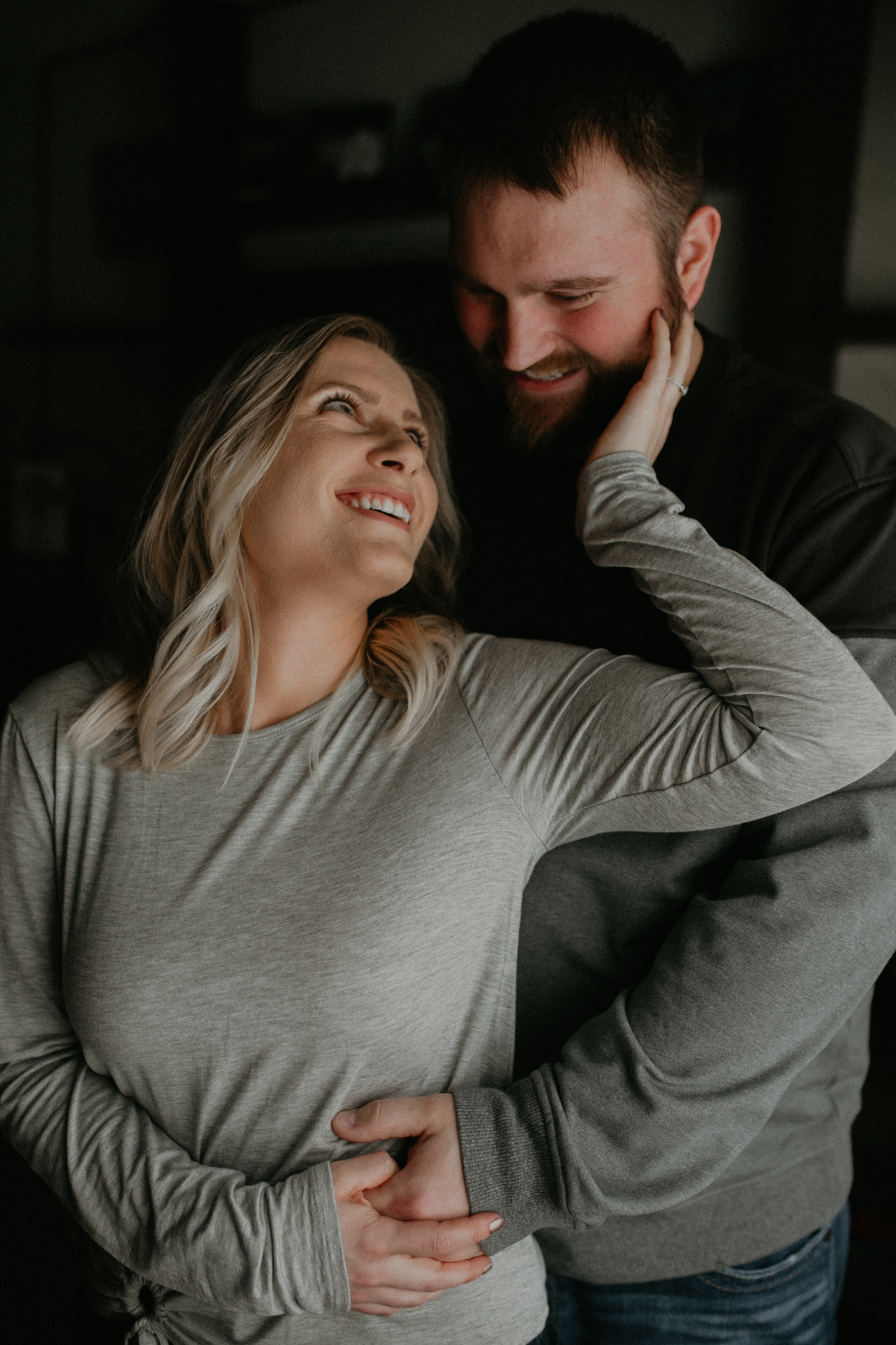 an engaged couple poses in front of their bay window during lifestyle session in Wisconsin with Andrea Wagner