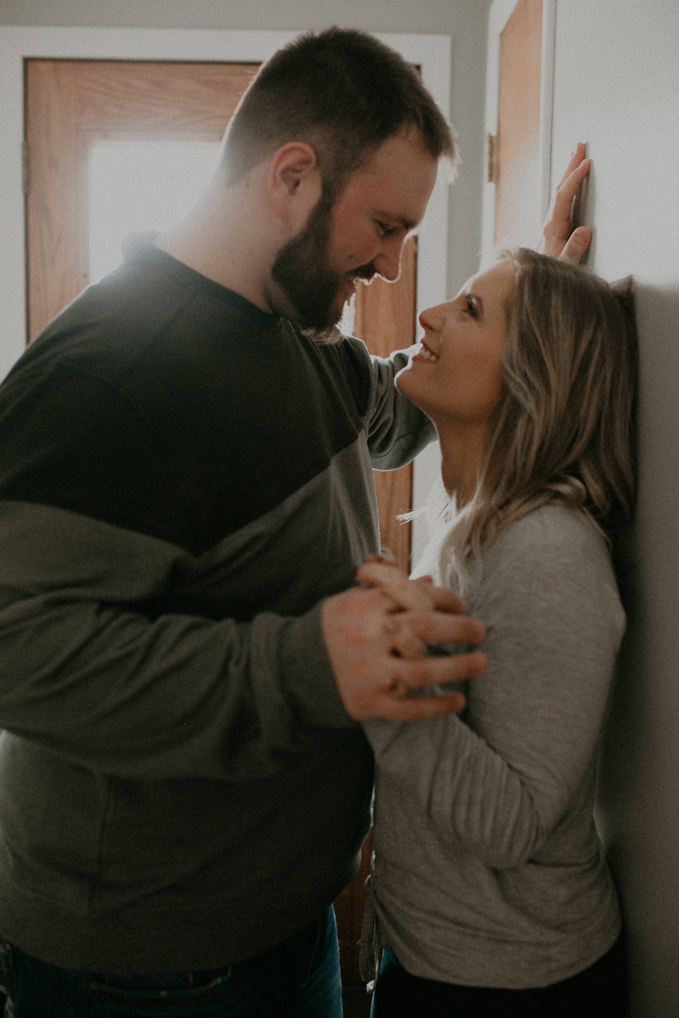 fiance lovingly stares at her soon-to-be husband during engagement photos in their home