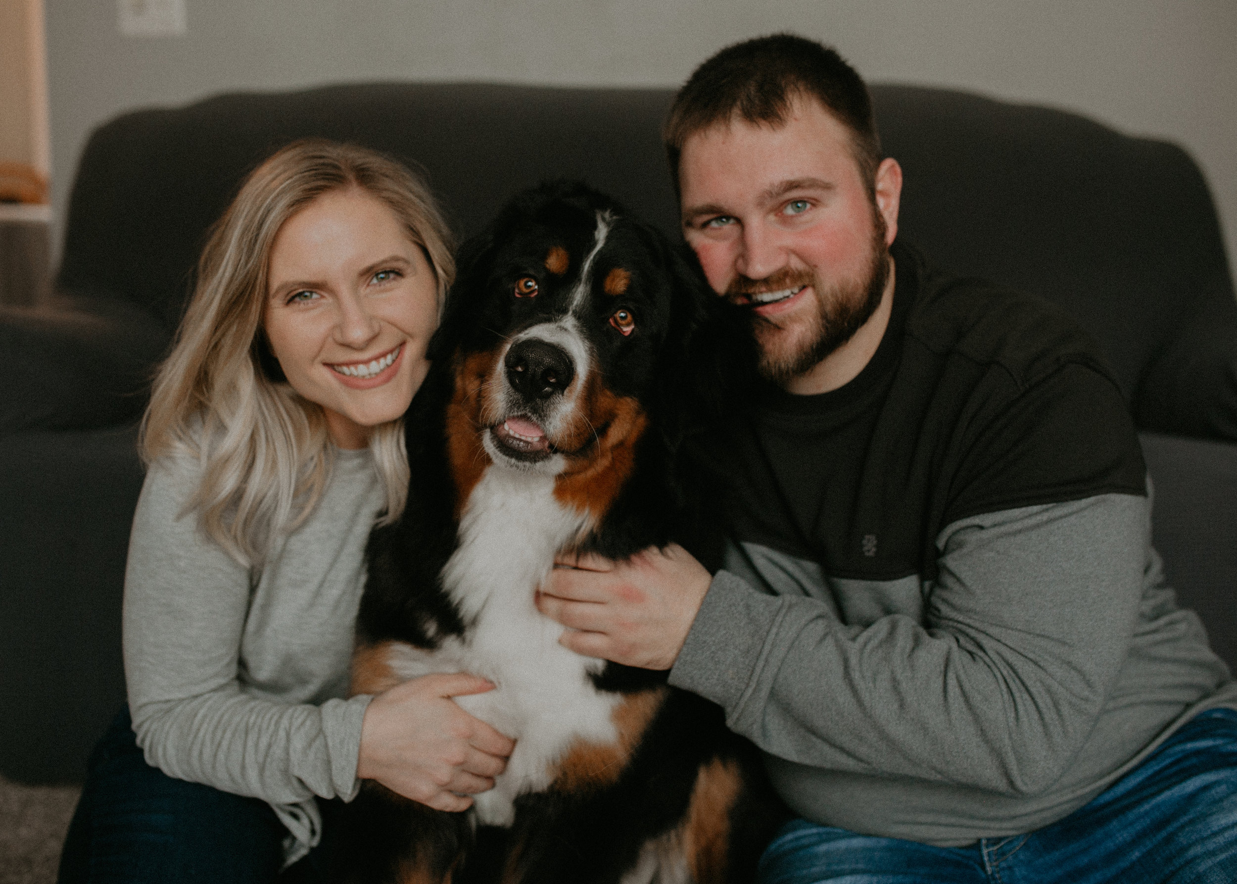  happy engaged couple poses with their Bernese mountain dog in their home in central WI 