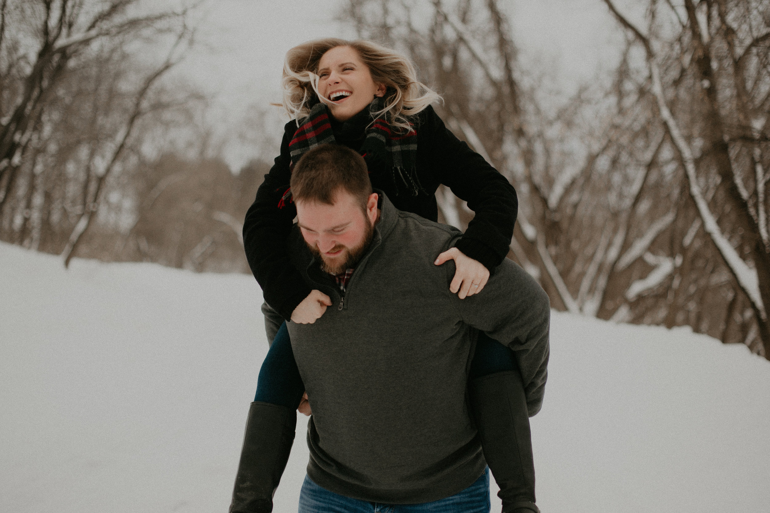  happy flirty couple twirls in the snow during their engagement session with Andrea Wagner near Wausau WI 