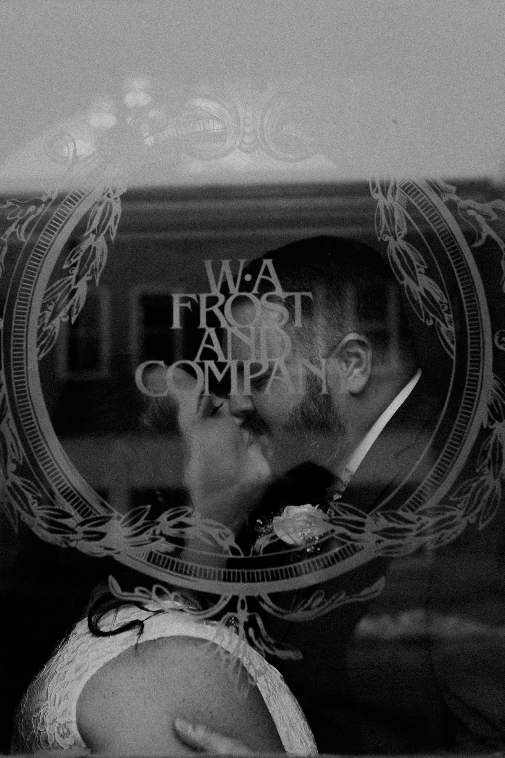 A black and white photo of a married couple kissing at W.A. Frost in the window