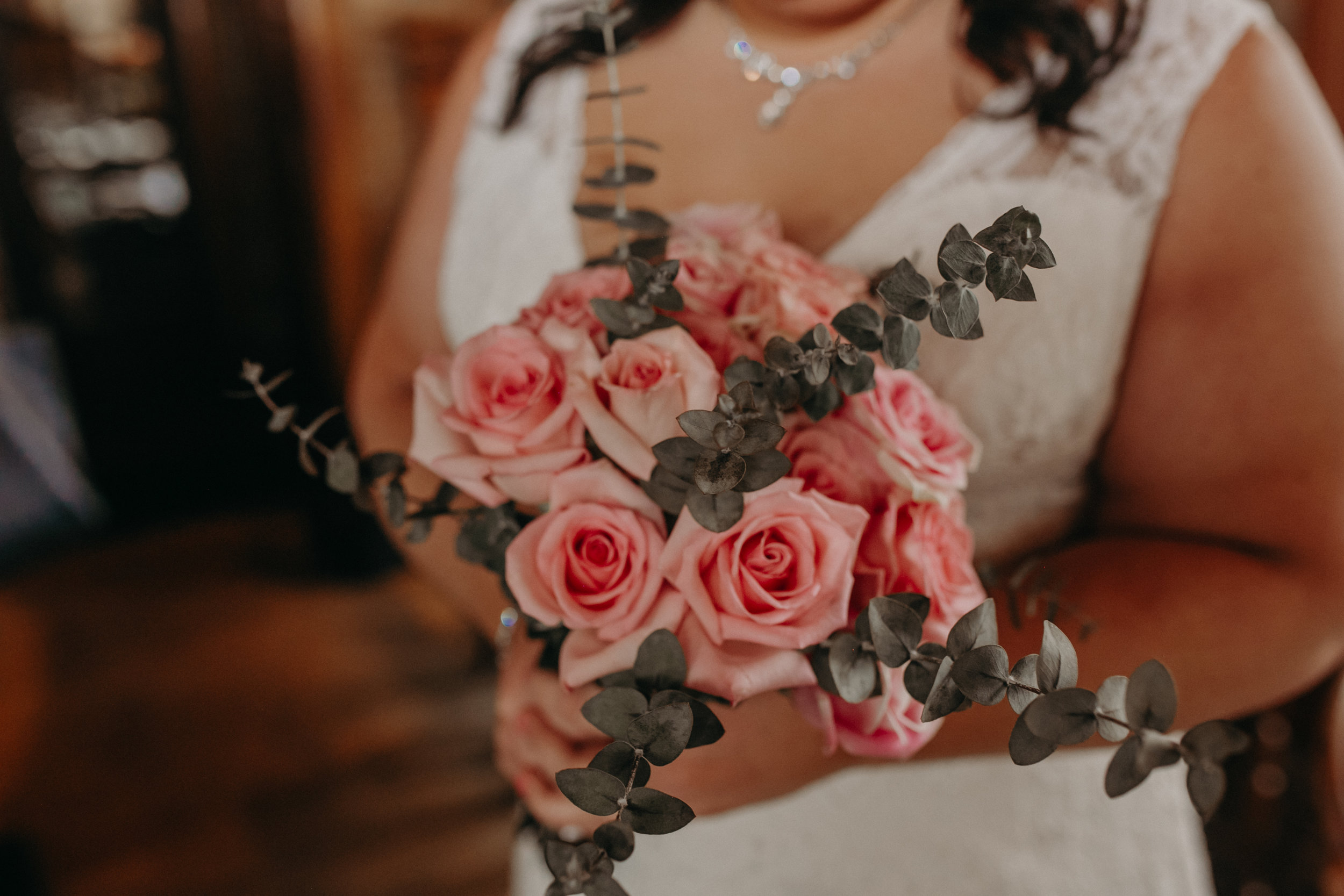 A bride at W.A. Frost holds her wedding bouquet made from pink roses and eucalyptus