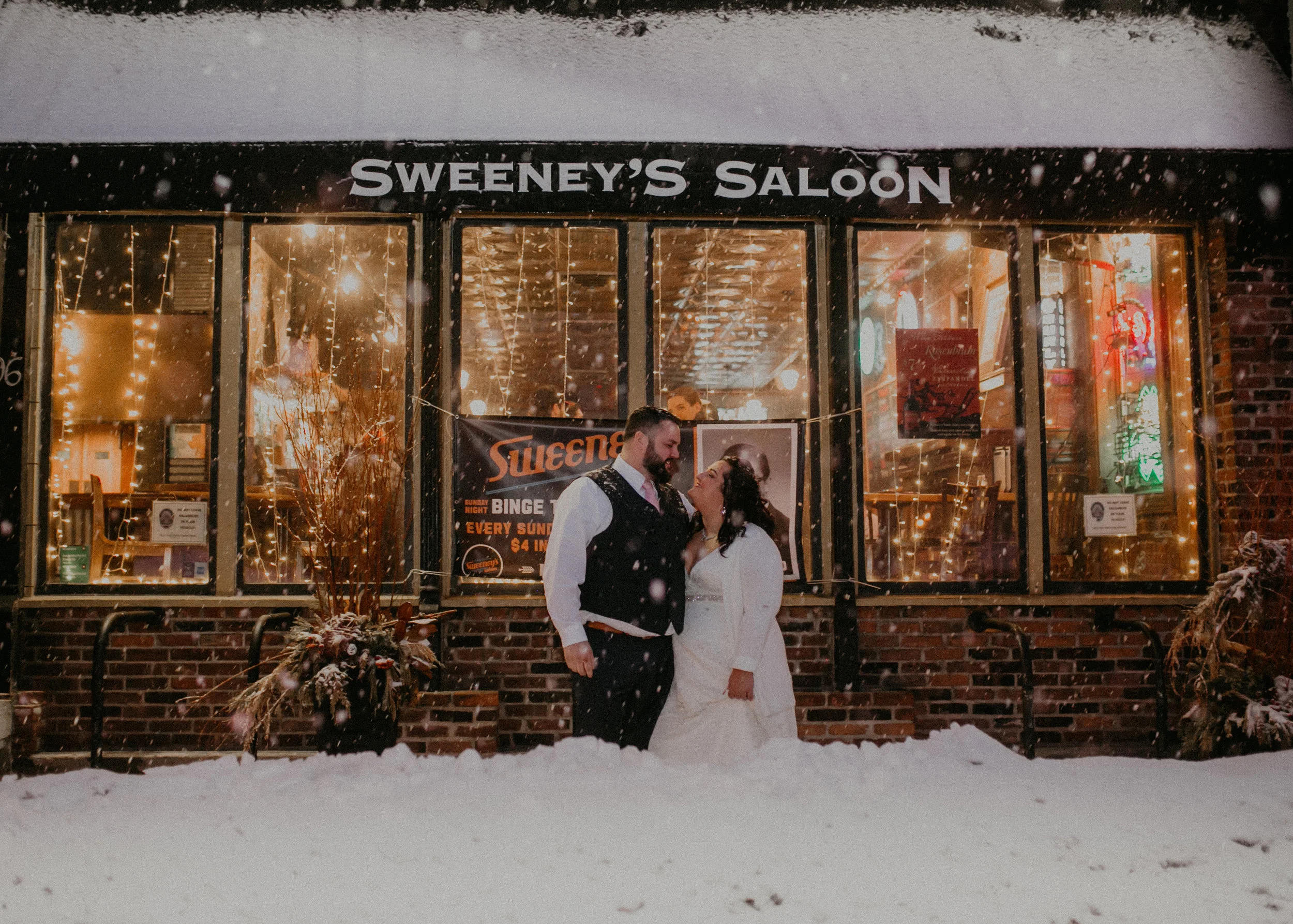 Andrea Wagner Photography captures a couple just married in front of Sweeney’s Saloon in St Paul MN during a snow storm winter wonderland