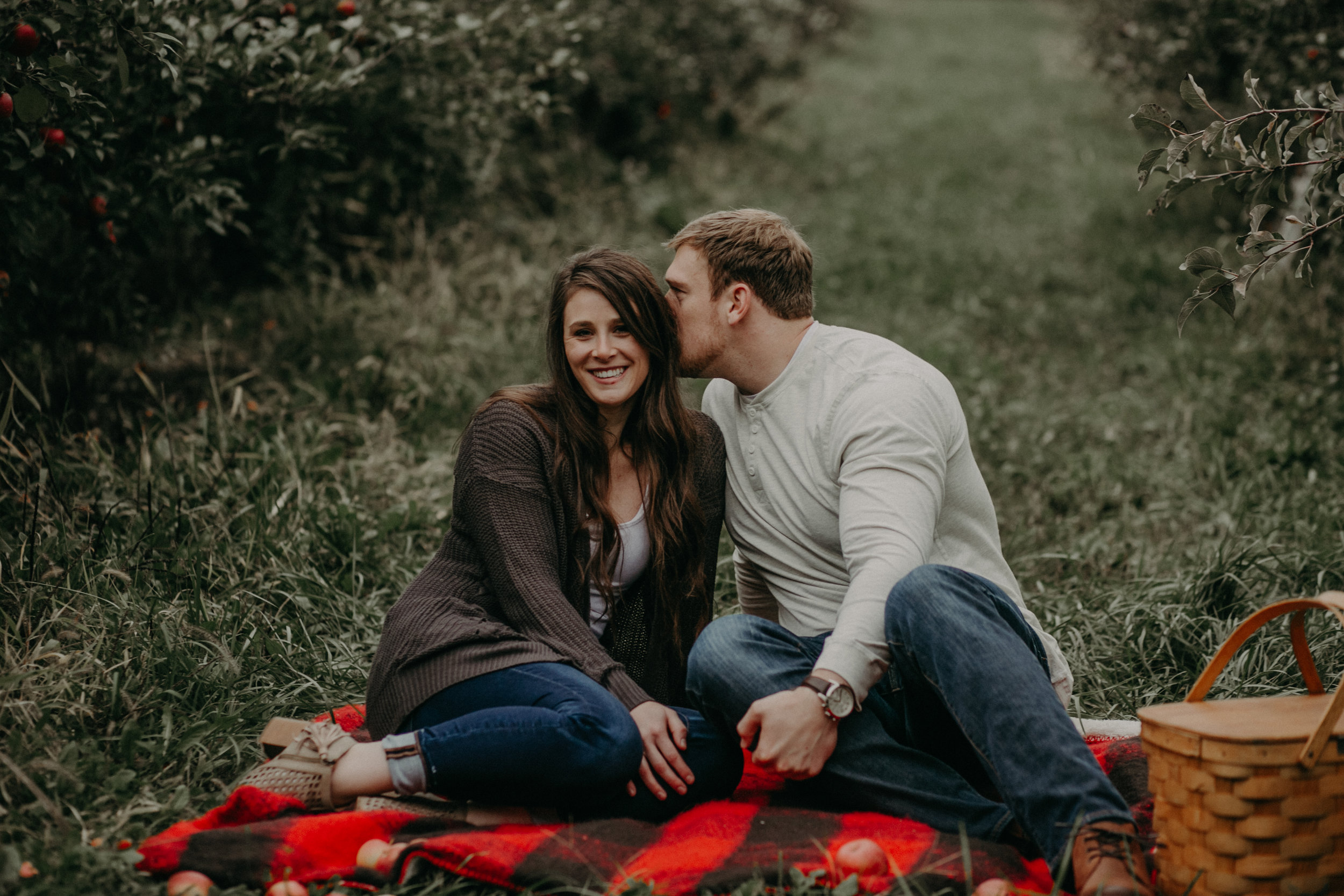  A man whispers into his fiancés ear during their engagement session in Hastings MN with Andrea Wagner Photography 