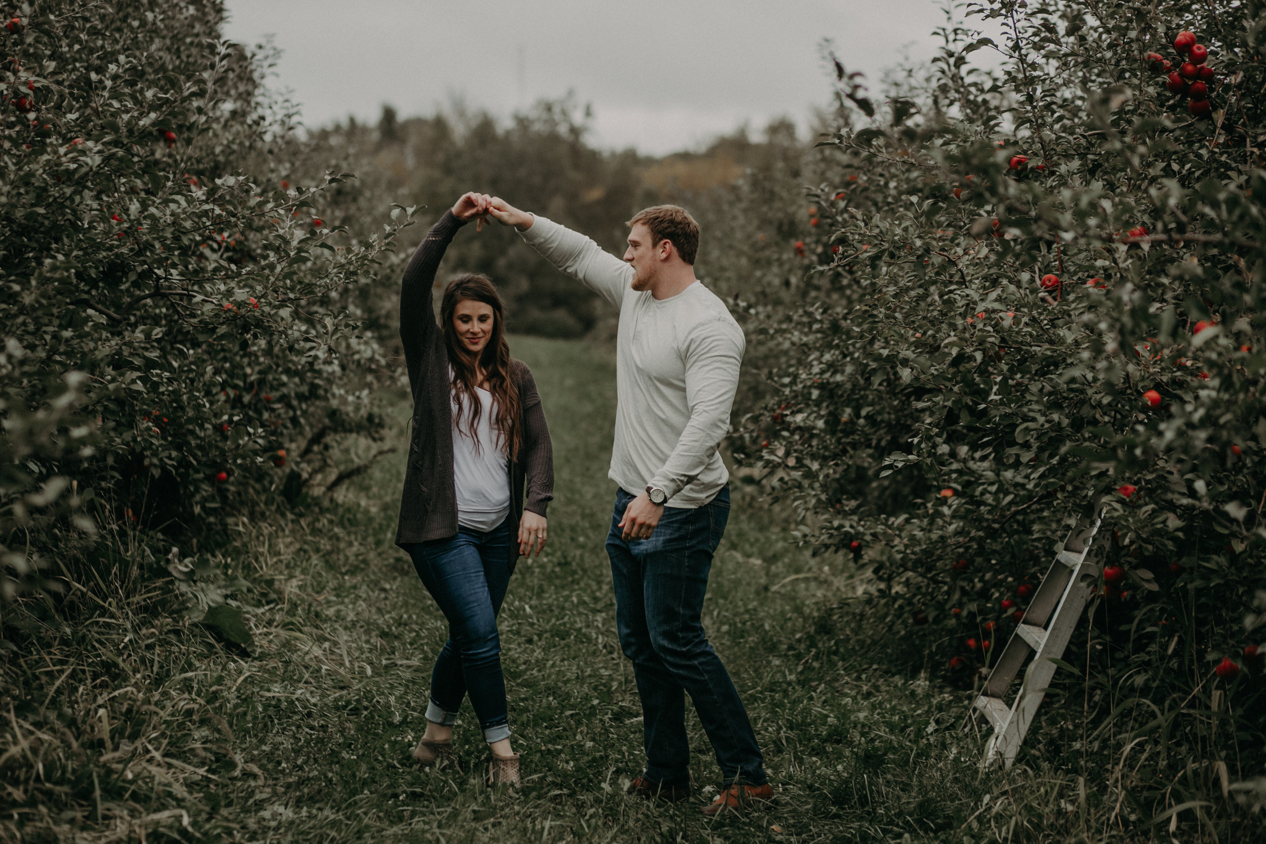 A couple dances amongst the apple tree orchard in Hastings MN during their engagement session