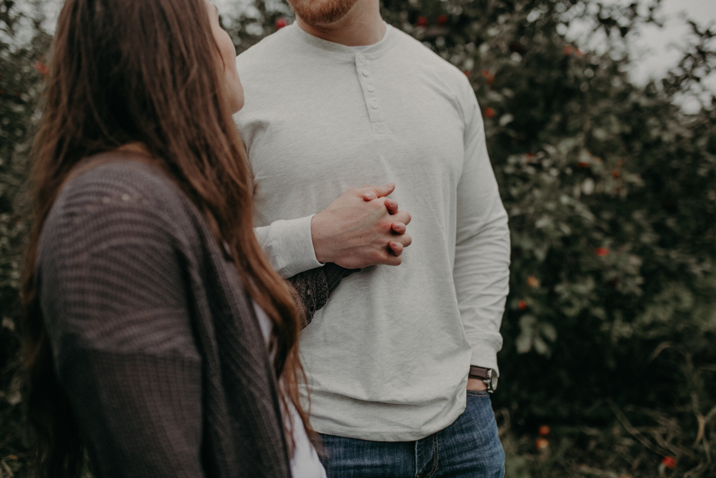 Hudson Wisconsin couple holds hands during their engagement session at an apple farm in October 2019