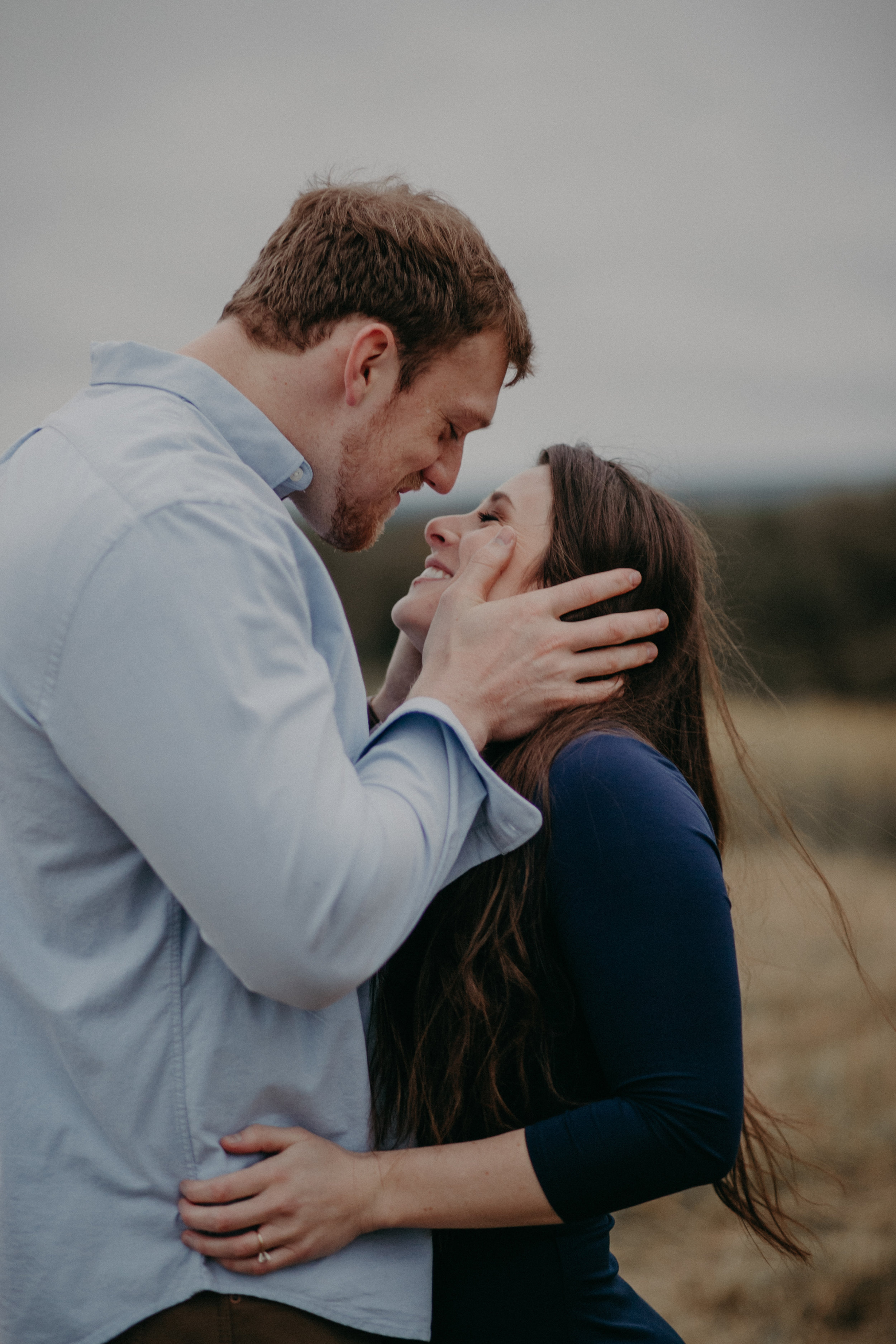  A man pulls his fiancé in for a romantic sexy kiss during their engagement session overlooking the St Croix River in Hastings MN 