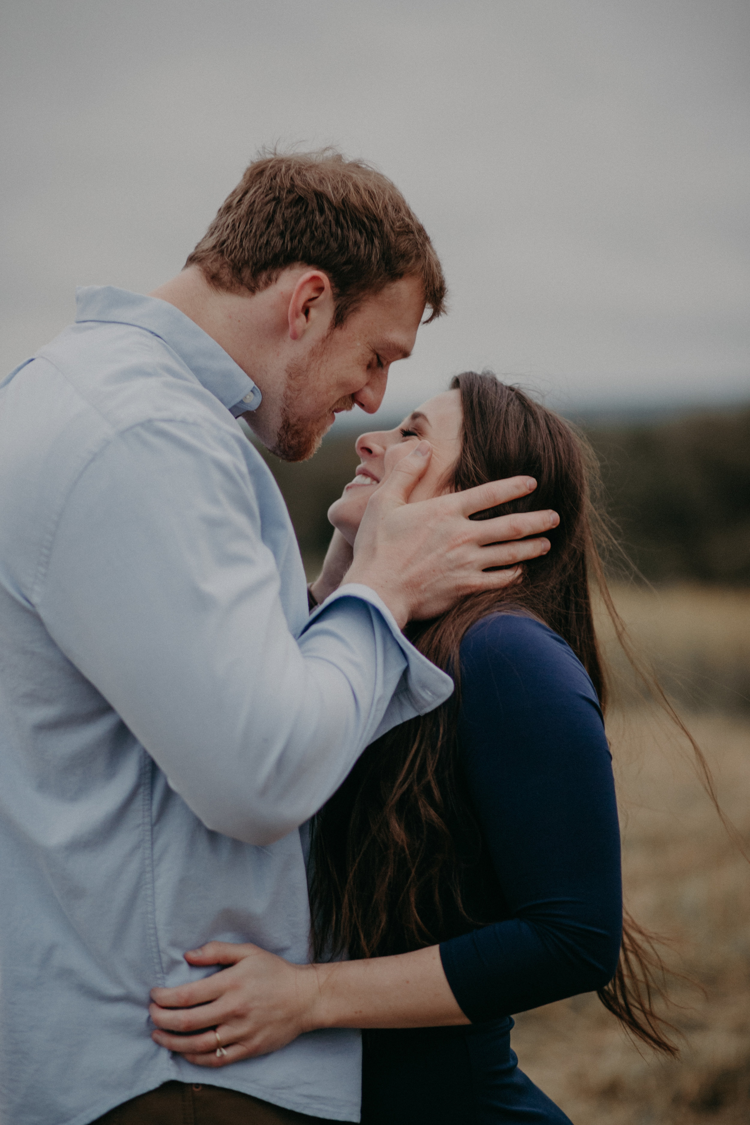 A man pulls his fiancé in for a romantic sexy kiss during their engagement session overlooking the St Croix River in Hastings MN