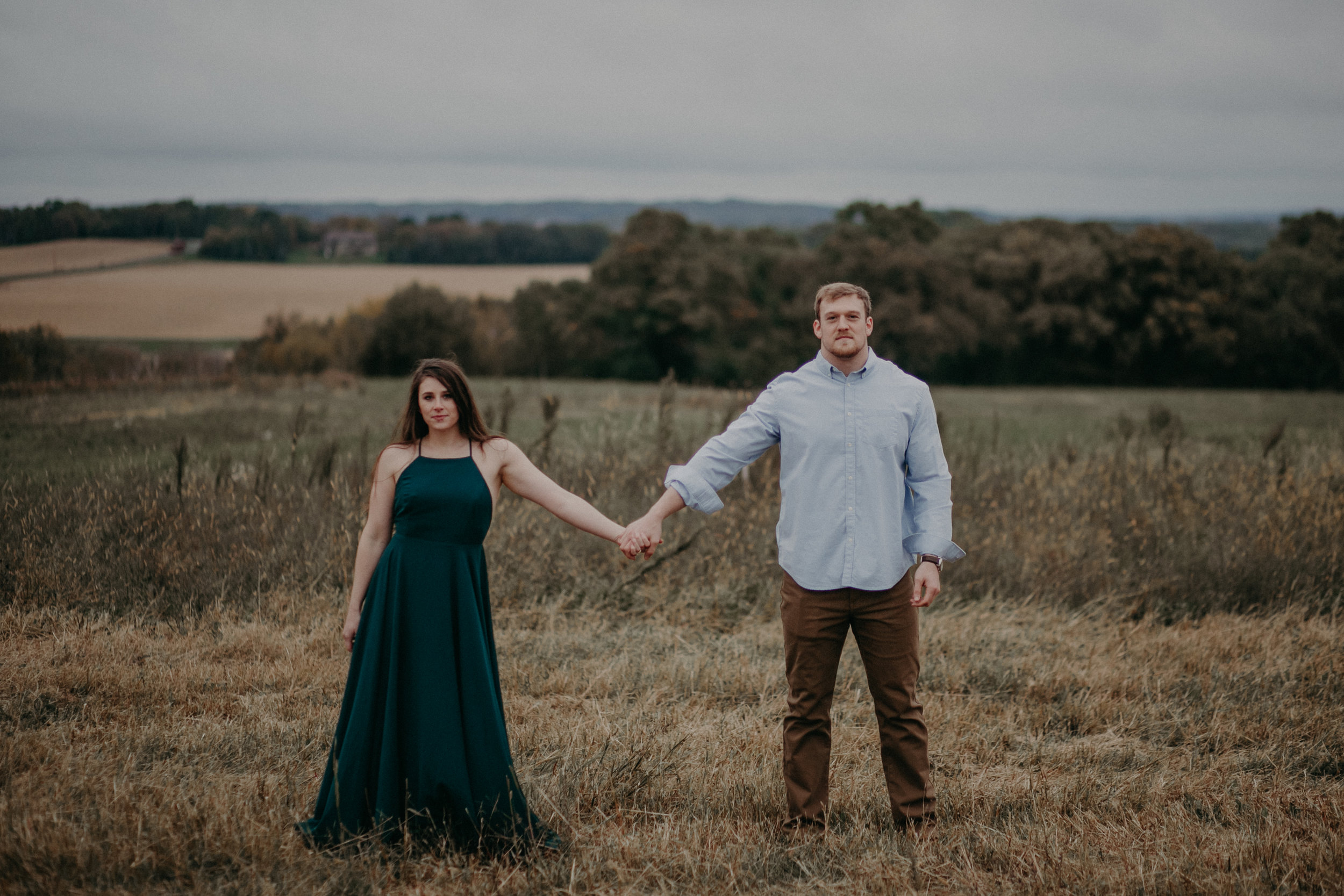 An engaged couple poses fiercely while holding hands side by side during their engagement session in Hastings MN