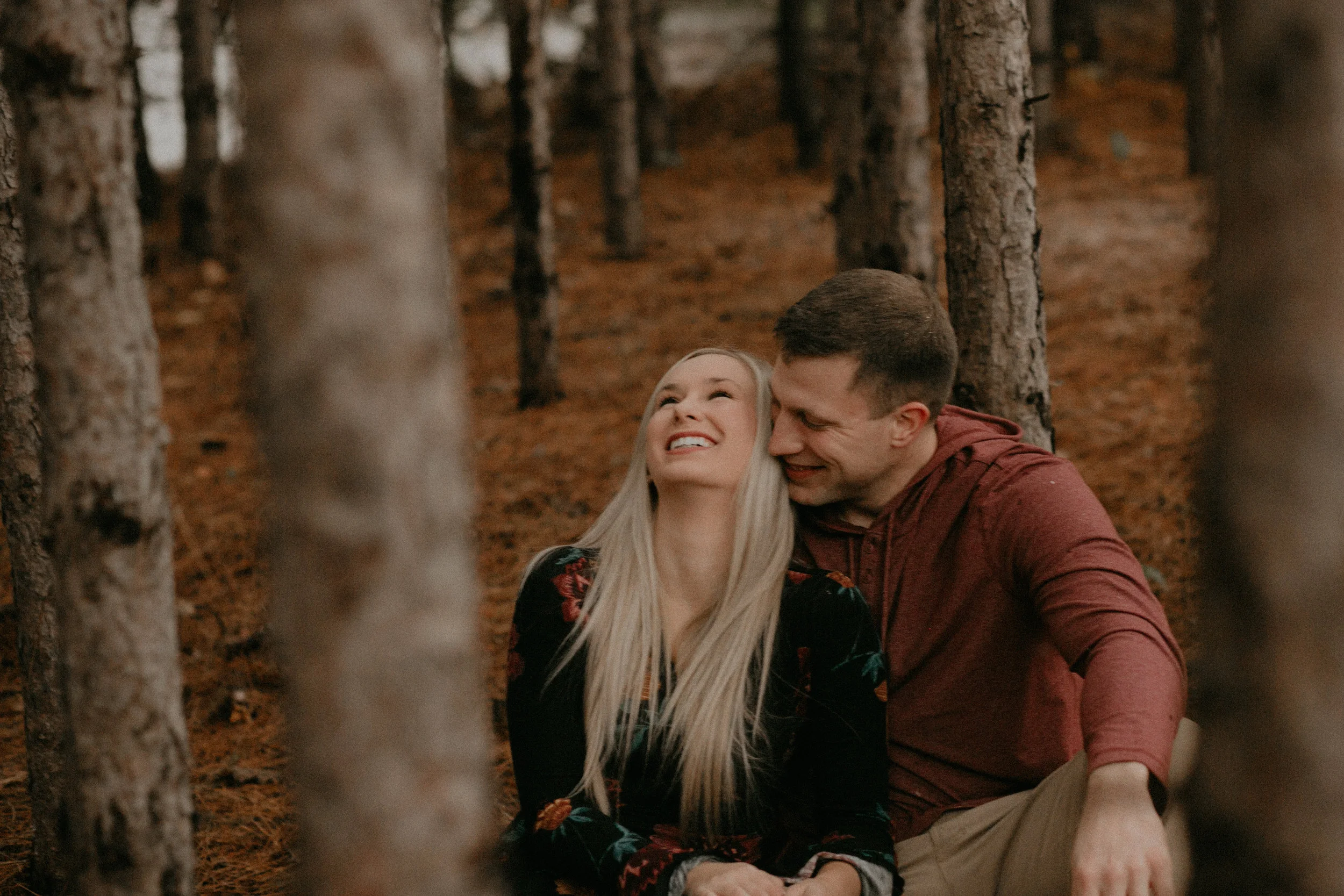 a man makes his fiancé laugh in the forest at Burlap and Bells in Black River Falls WI
