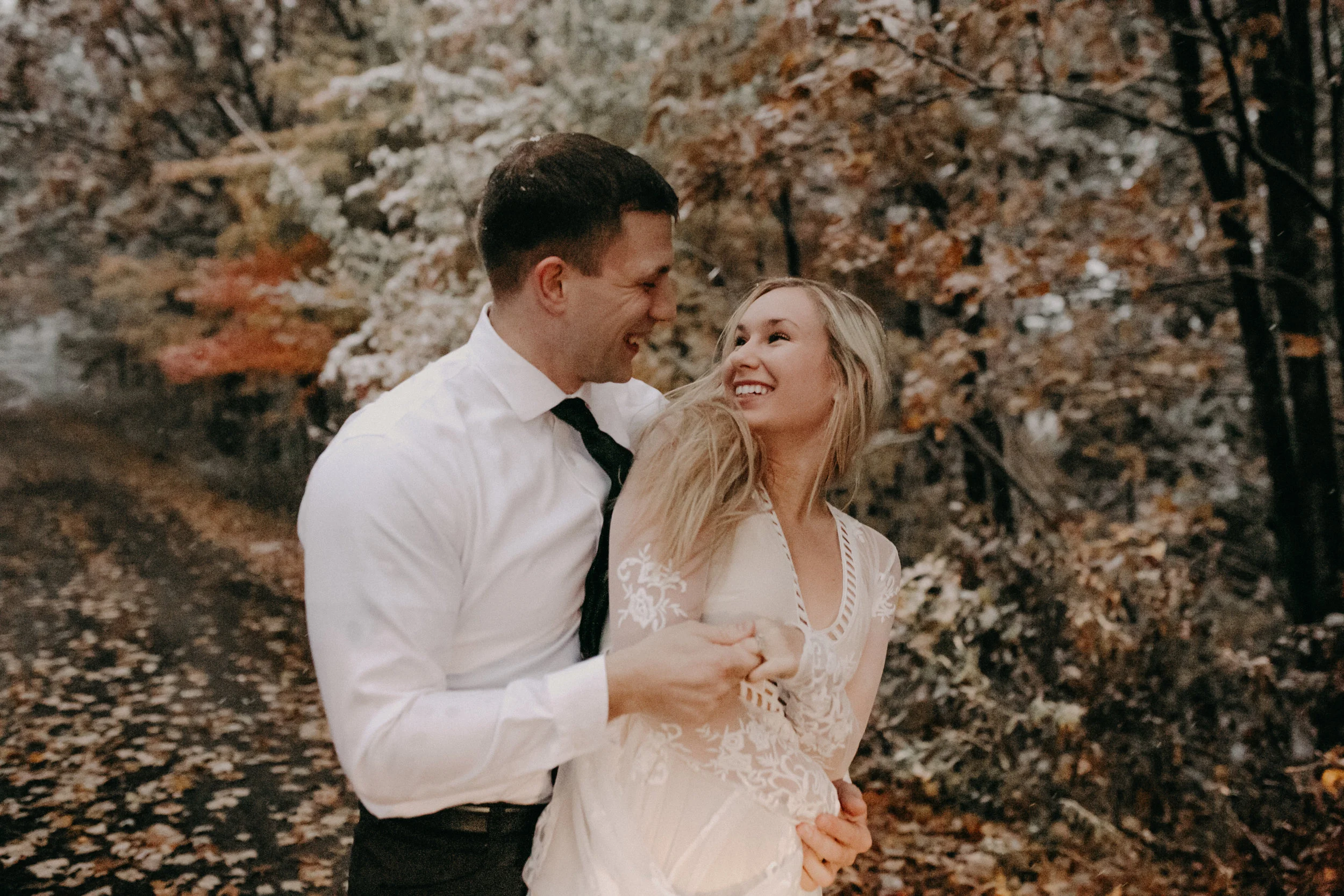 a beautiful happy woman in a lace white dress spins inter her fiancé during their engagement photos in Black River Falls WI