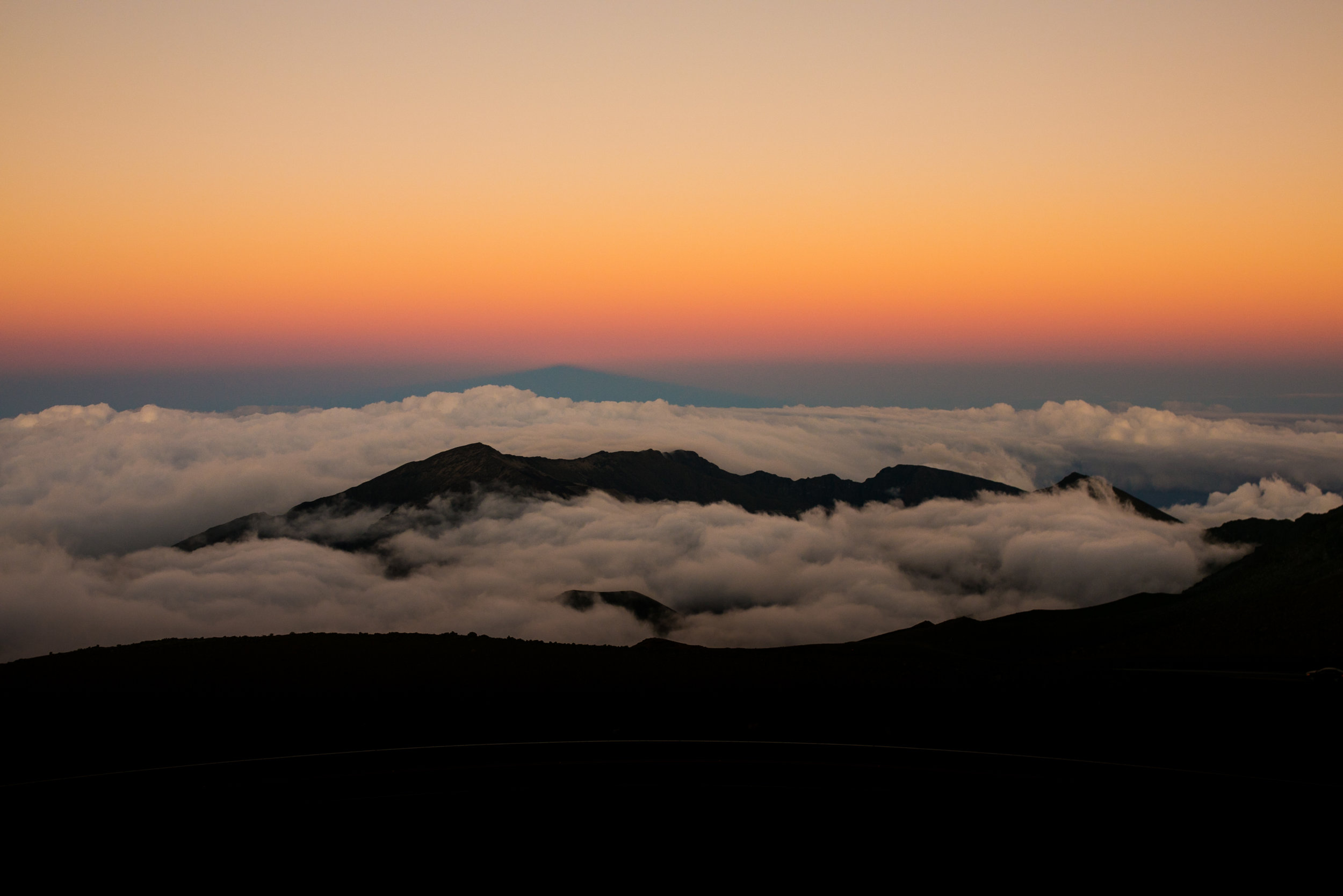  pink and orange sunset above the clouds over Haleakala Crater 