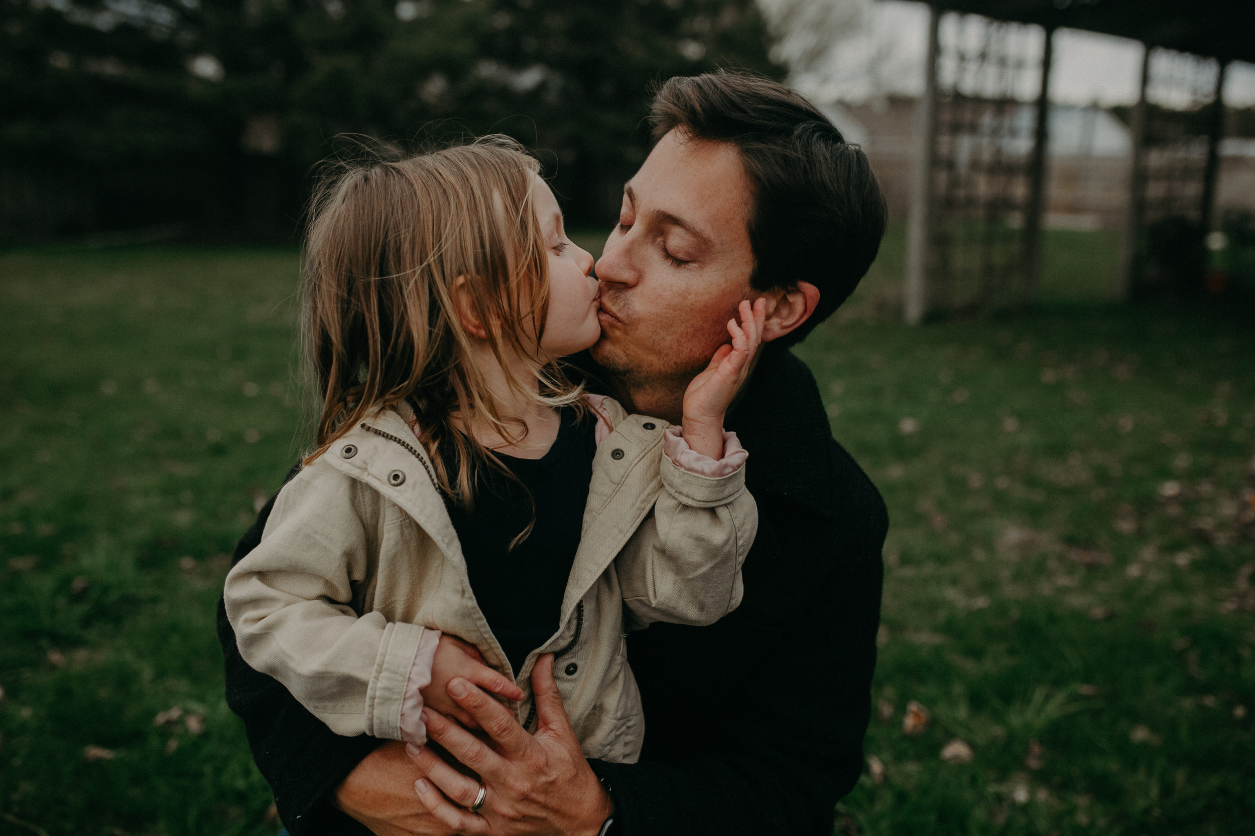  a toddler kisses her daddy during their photo shoot on Madeline Island during the Madeline Island Marathon weekend 