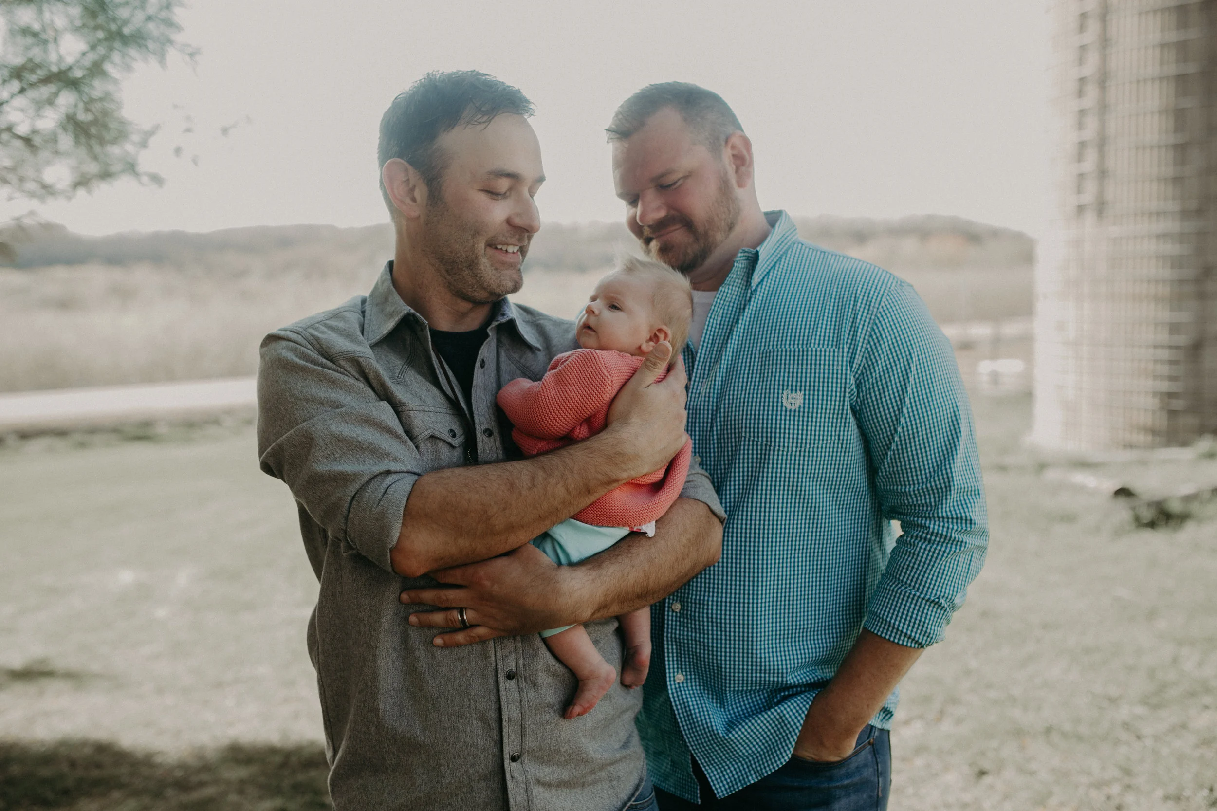 same-sex couple holds their newborn daughter on their farm in River Falls WI