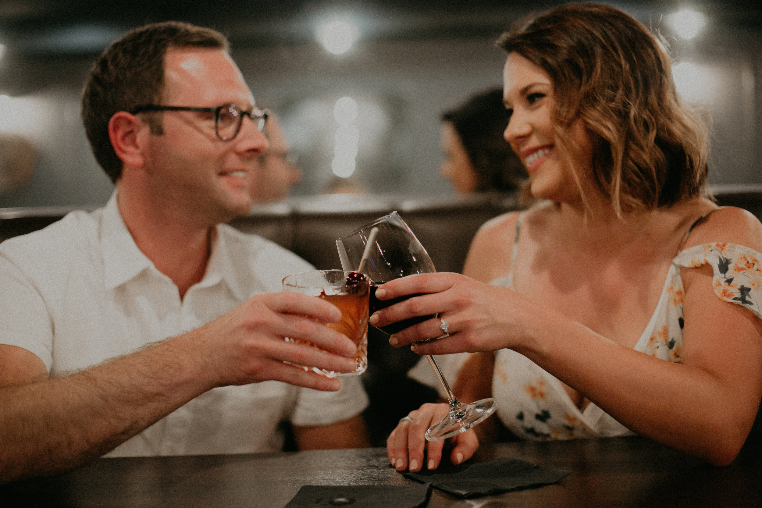  a couple cheers their drinks at LoLo American Kitchen in Hudson WI during their engagement session 